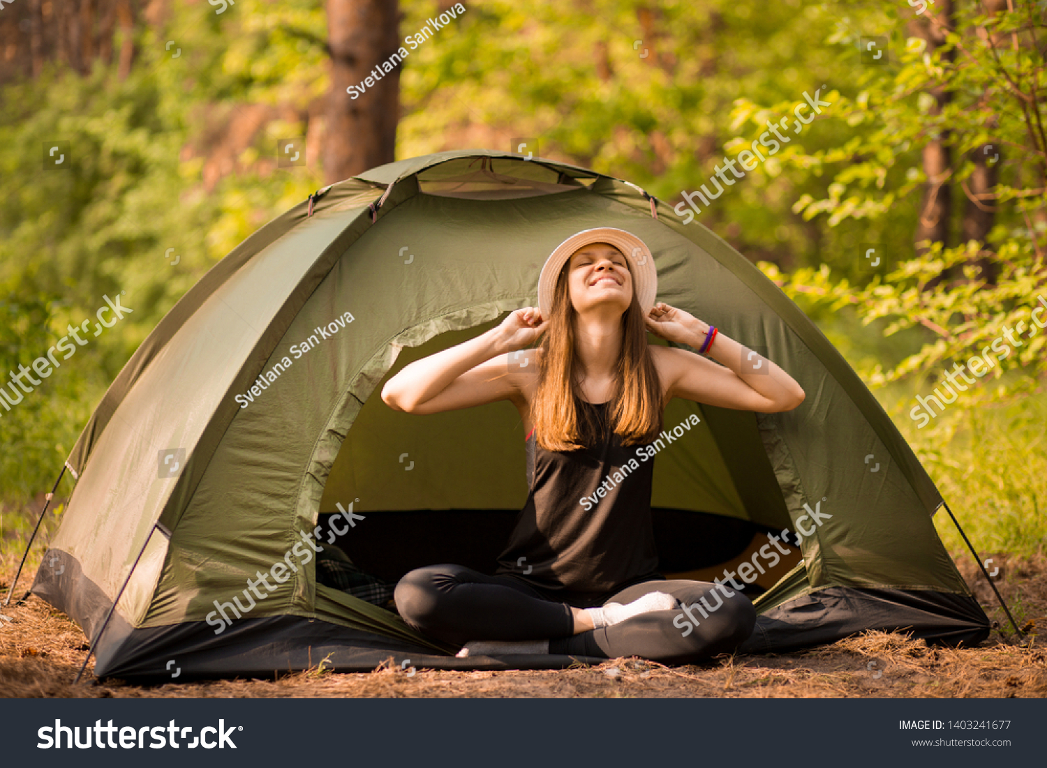 Happy hipster cute teen girl with hands enjoying sunrise outside the tent. camping in forest. Enjoy nature freedom #1403241677