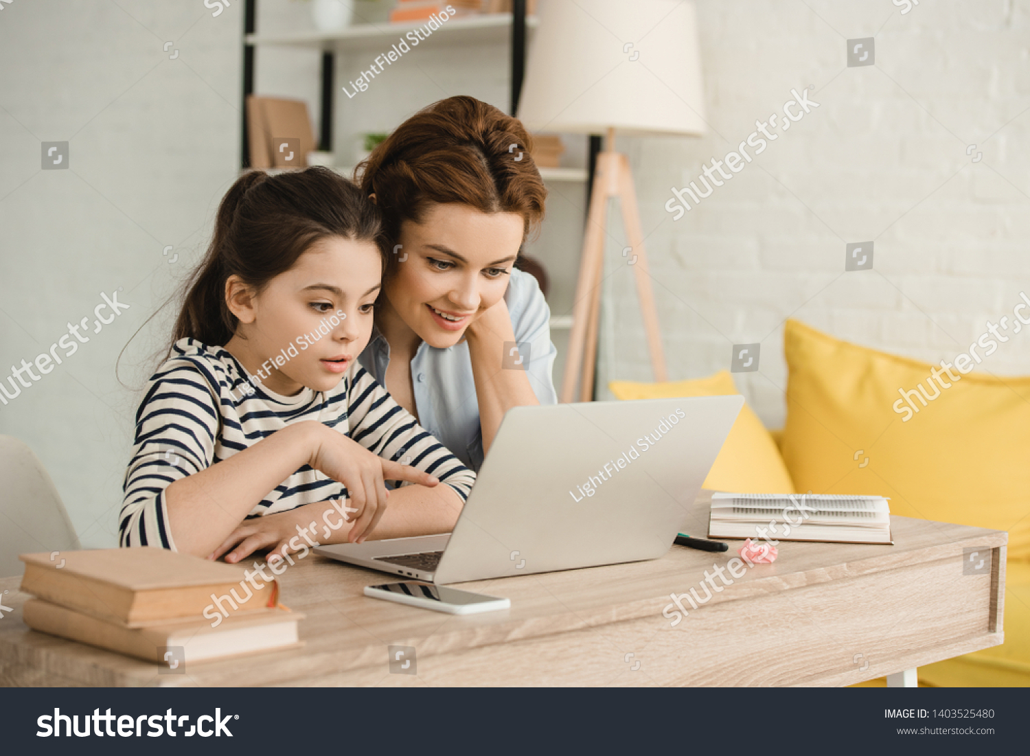 surprised mother and daughter using laptop while doing homework together #1403525480