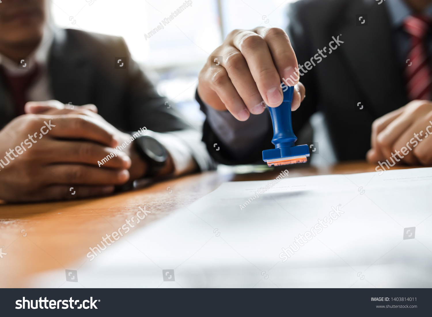 Businessman stamping with approved stamp on document at meeting. #1403814011