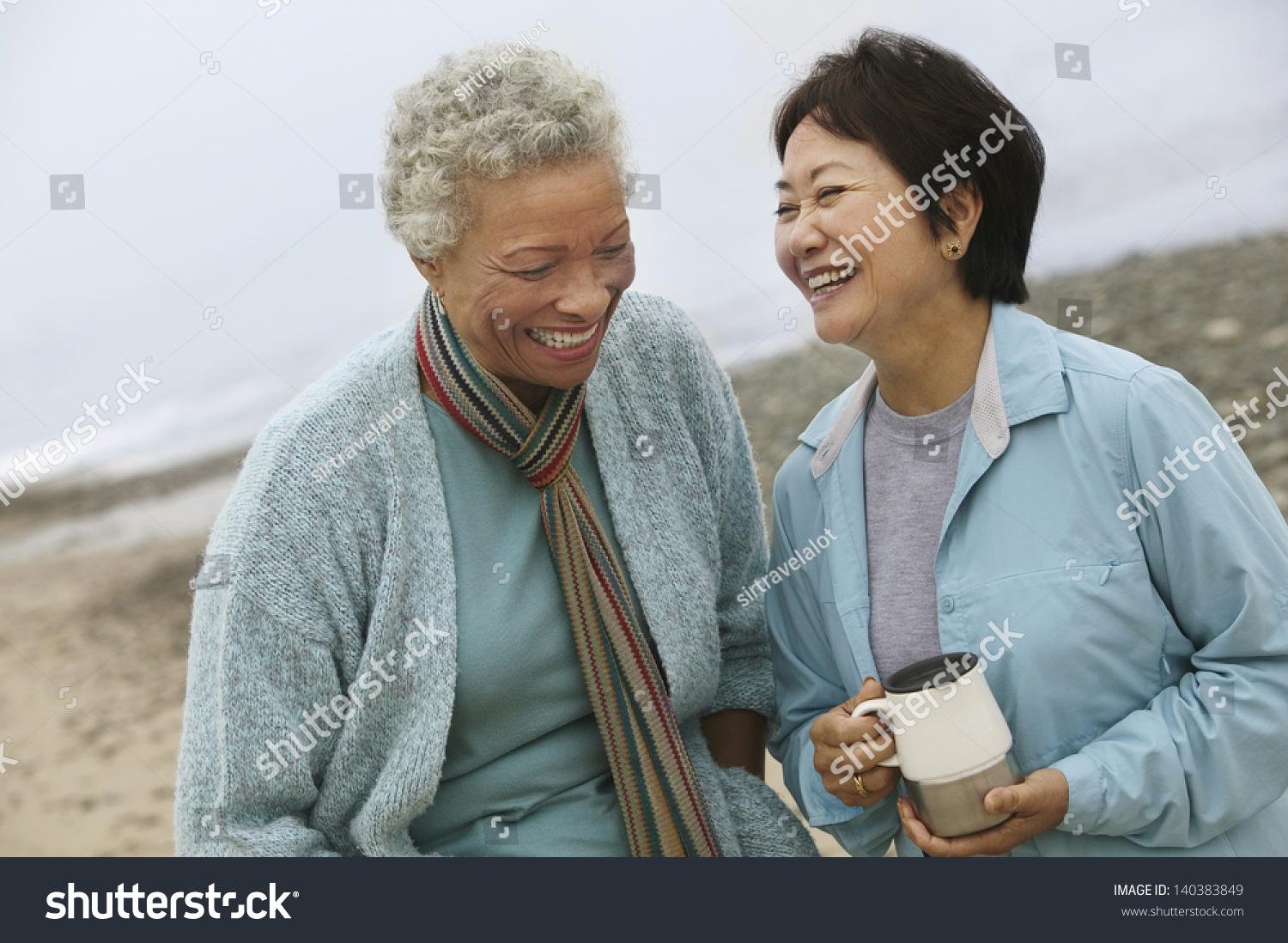 Two cheerful middle aged female friends talking on the beach #140383849