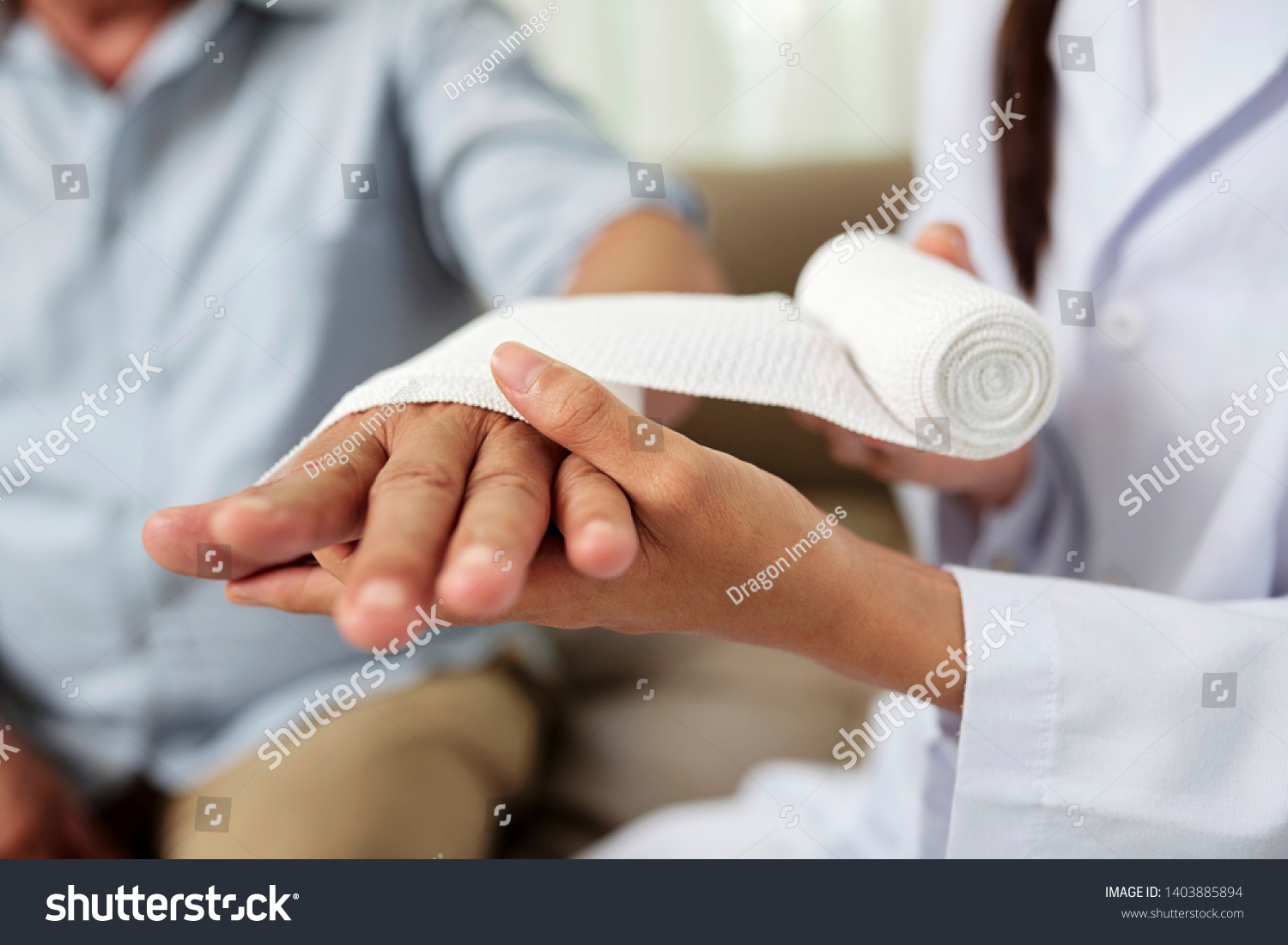 Close-up of female doctor putting a bandage on injured hand of senior man at hospital #1403885894
