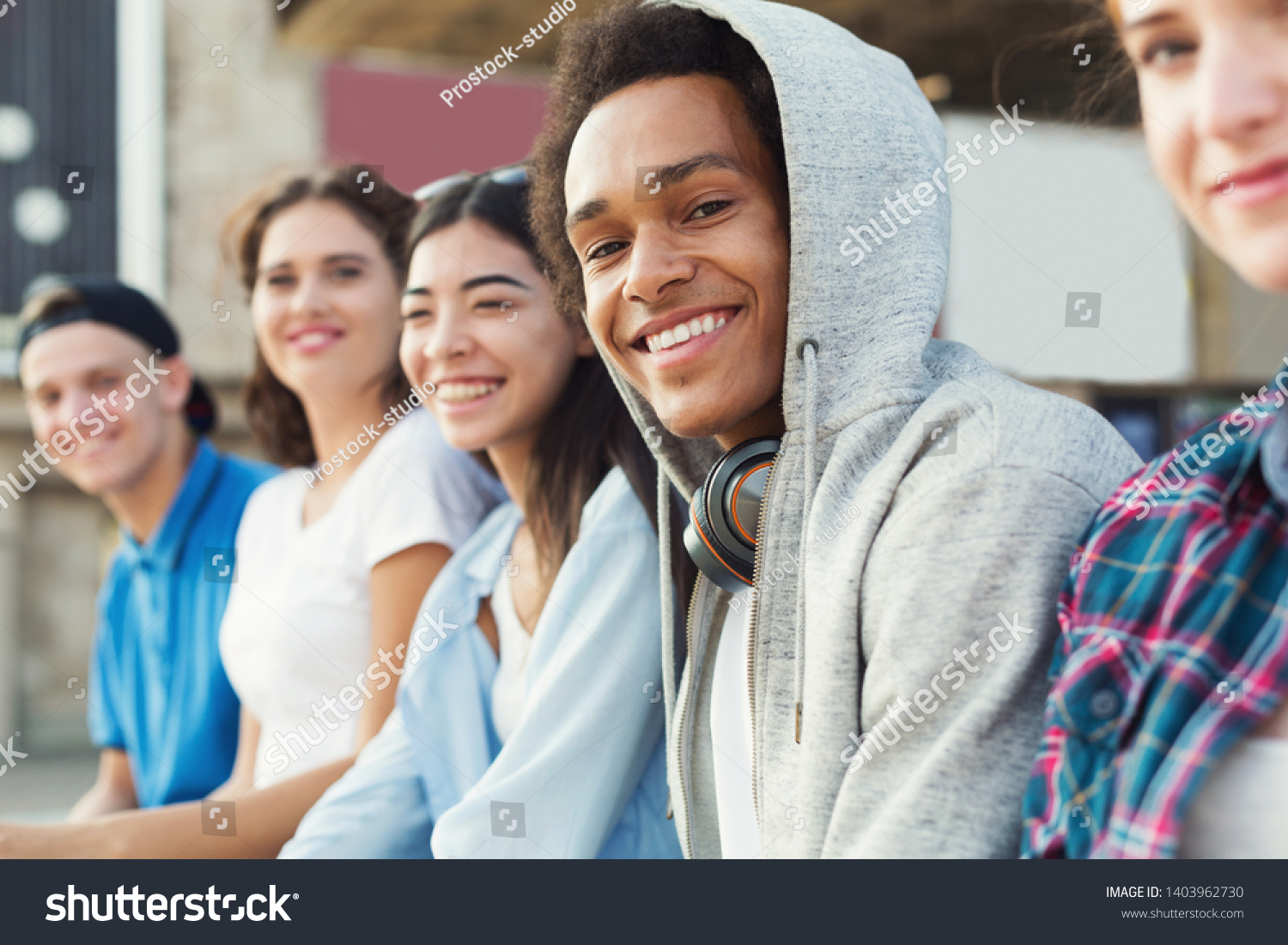 Multiethnic teen company spending time together, sitting outdoor, free space #1403962730