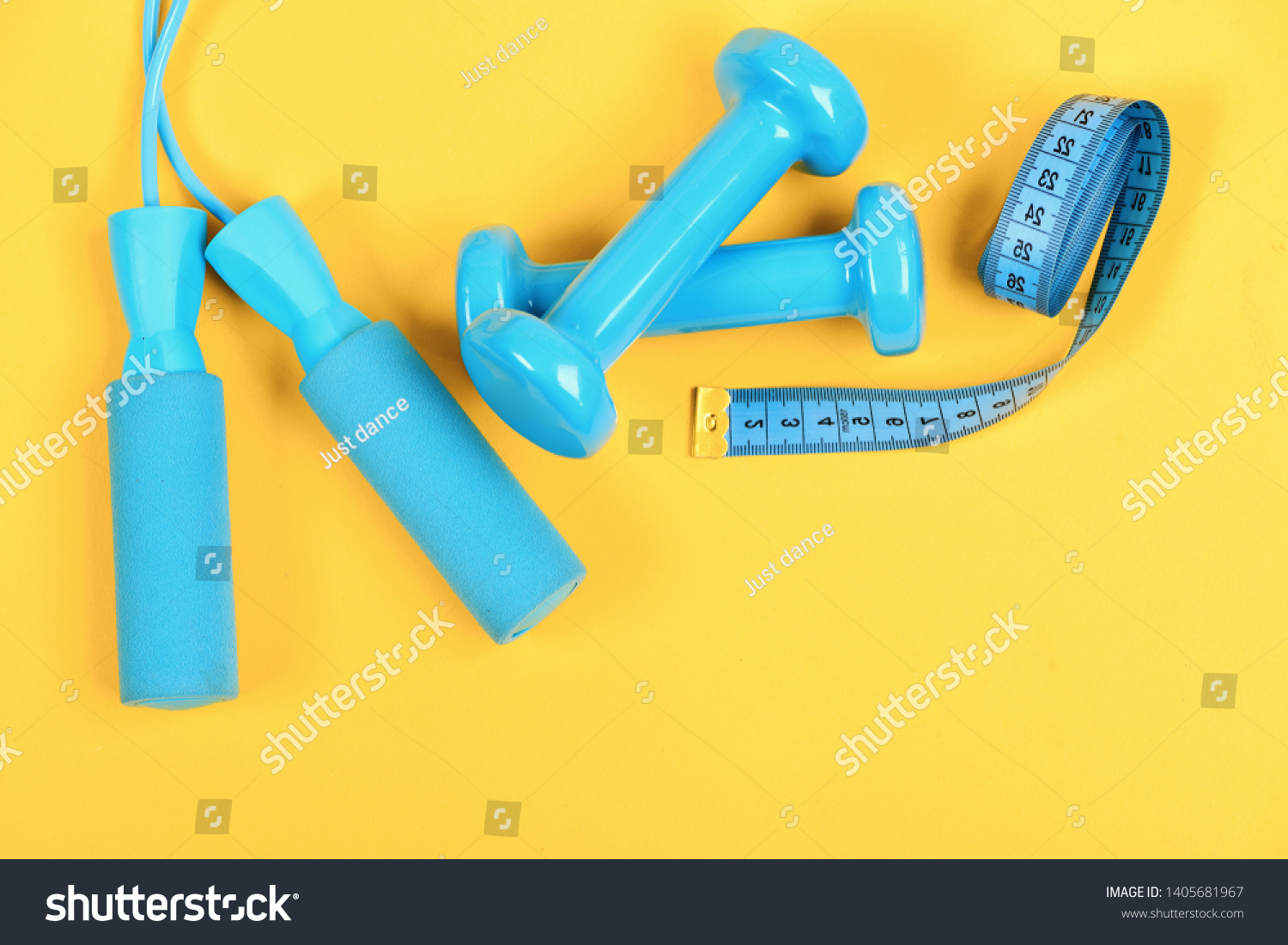 Healthy shape and sport concept. Dumbbells and jump rope in cyan color isolated on yellow background. Shaping and fitness equipment. Barbells and skipping rope next to measure tape roll, top view #1405681967