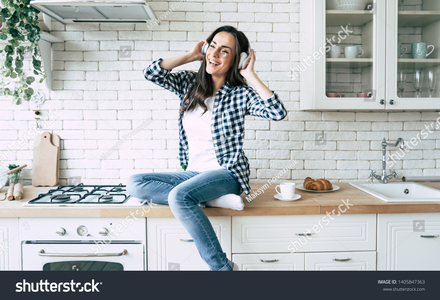 Relax at home. Beautiful happy young woman in headphones is listening music and have a fun on the kitchen. #1405847363