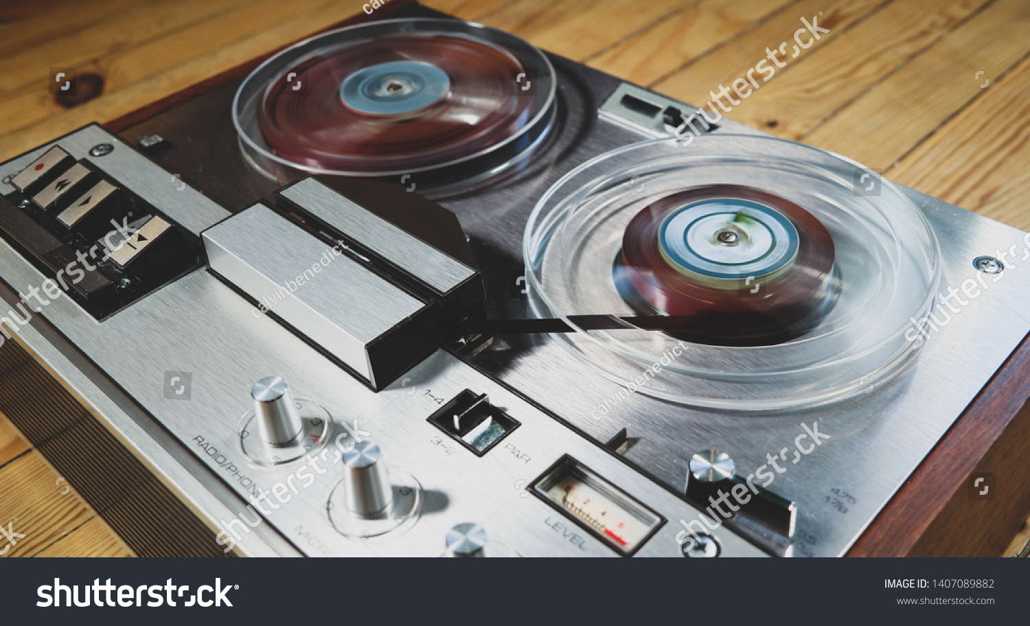 Vintage reel to reel tape recorder on a wooden floor #1407089882