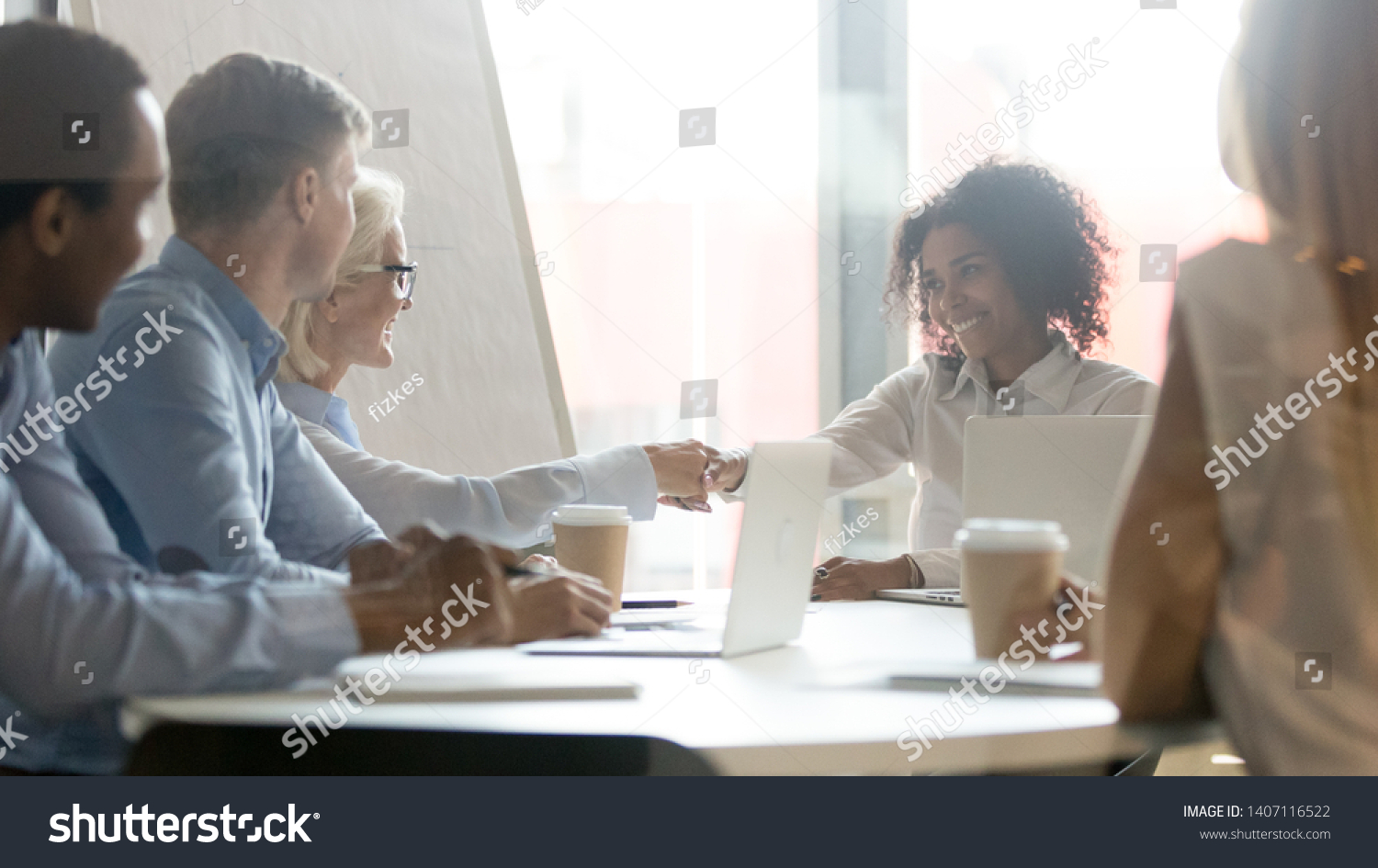 Smiling african female leader handshake partner client making commercial deal agreement at team meeting or group negotiations sitting at conference table shake hands thank for collaboration, respect #1407116522