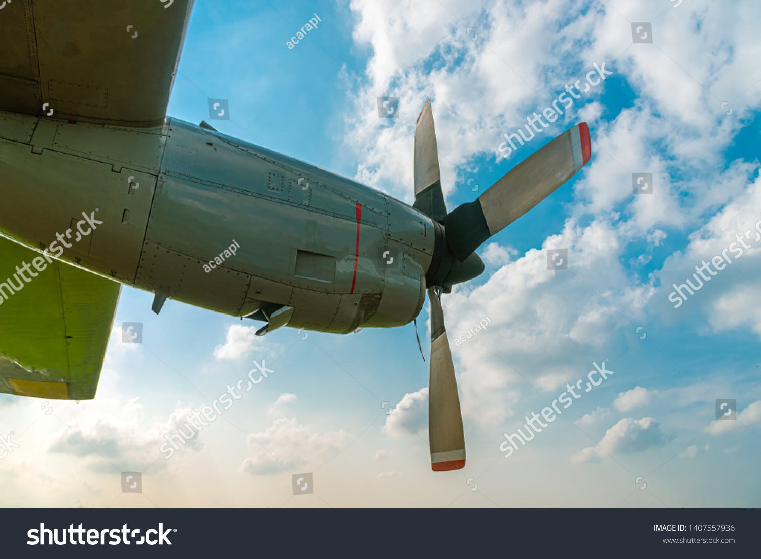 Aircraft Propeller and Spinner Engine on Airplane Wing Against Cloudy Blue Sky. Four Blade Aircraft Propeller. #1407557936