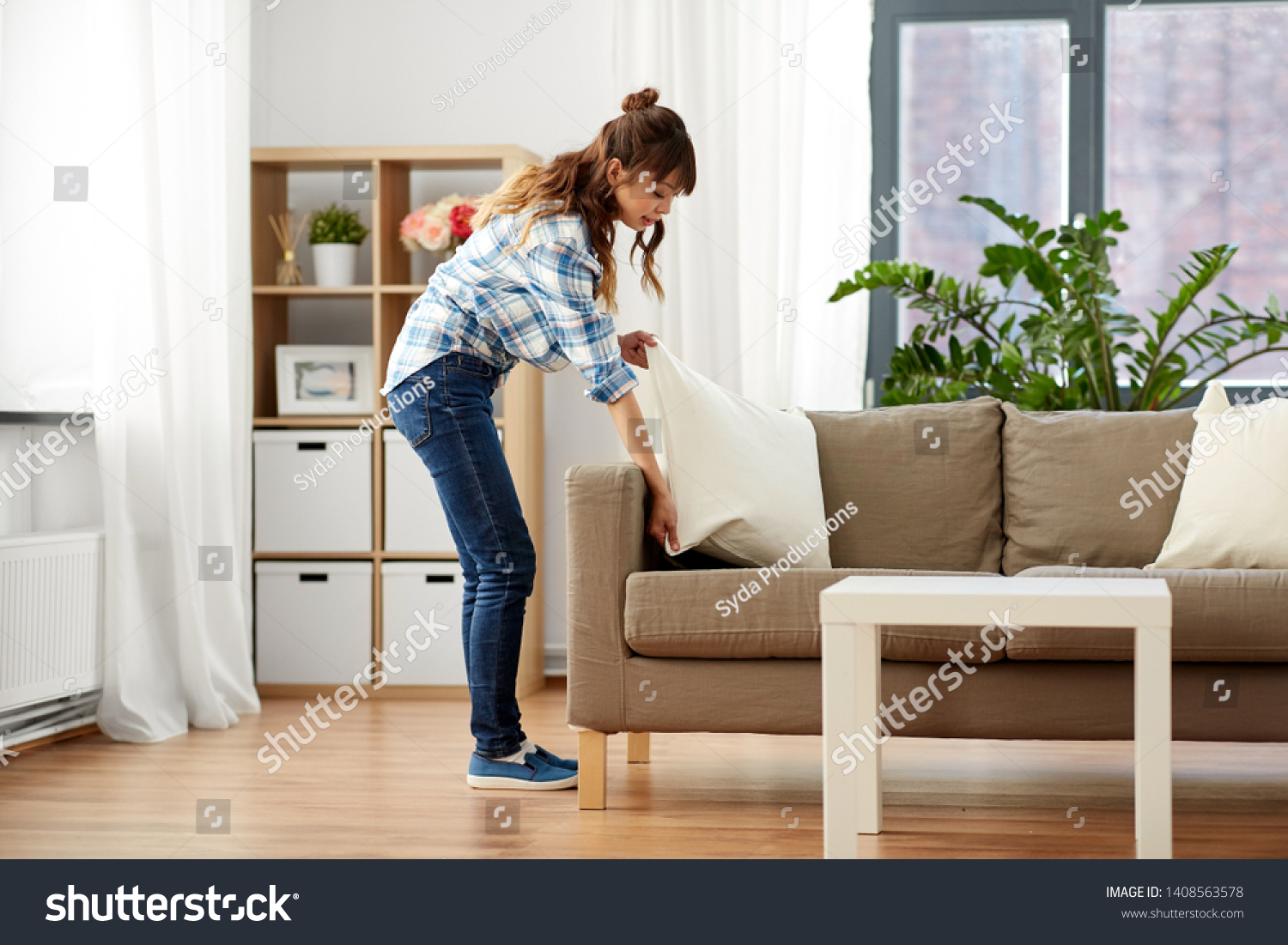 household, housework and cleaning concept - asian woman arranging sofa cushions at home #1408563578