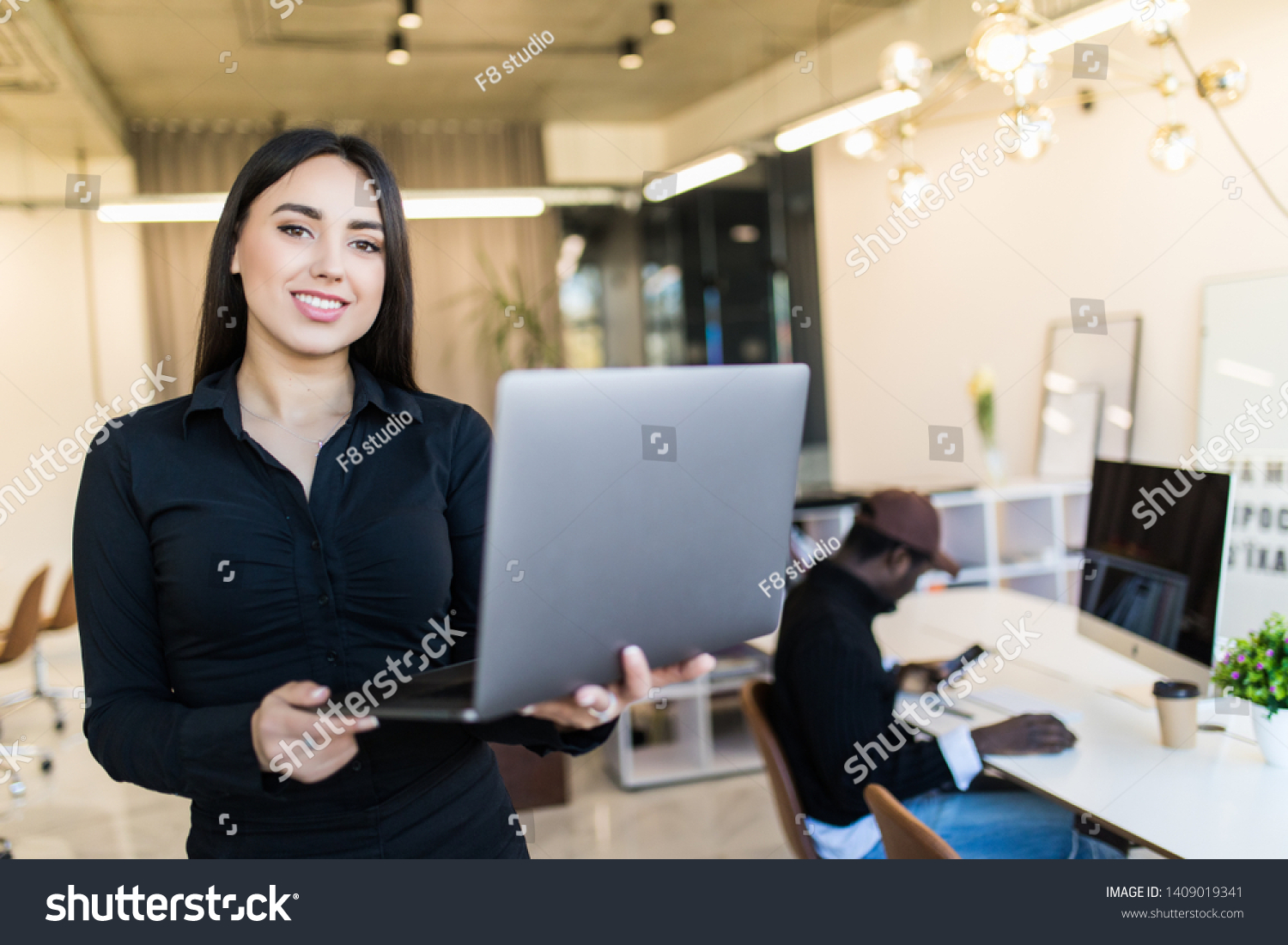 Elegant and cheerful businesswoman. Cheerful young beautiful woman in glasses looking at camera with smile while sitting at her working place #1409019341