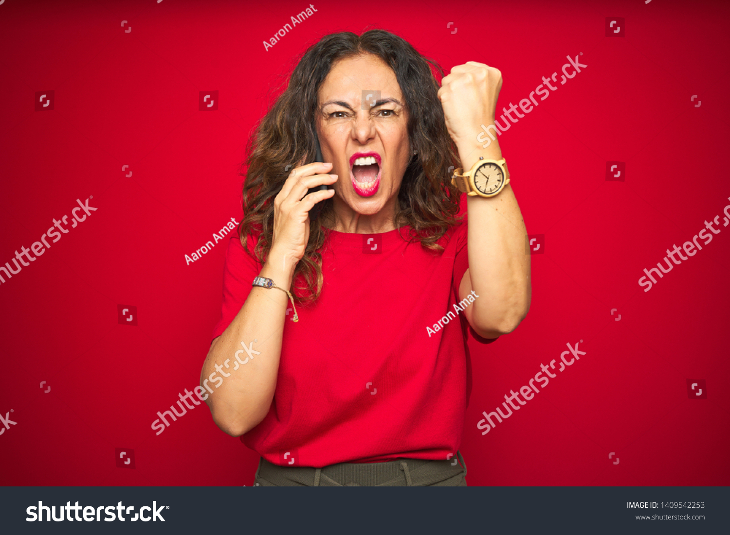 Middle age senior woman talking on the phone over red isolated background annoyed and frustrated shouting with anger, crazy and yelling with raised hand, anger concept #1409542253