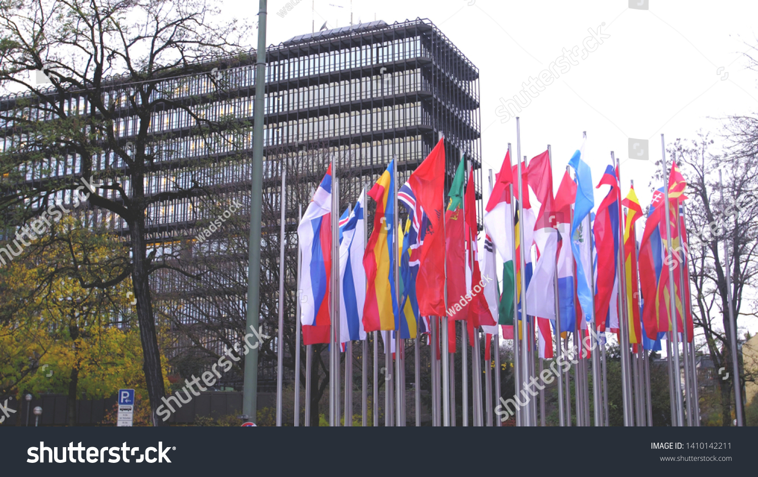 Waving european vertical flags next to a modern government building. #1410142211