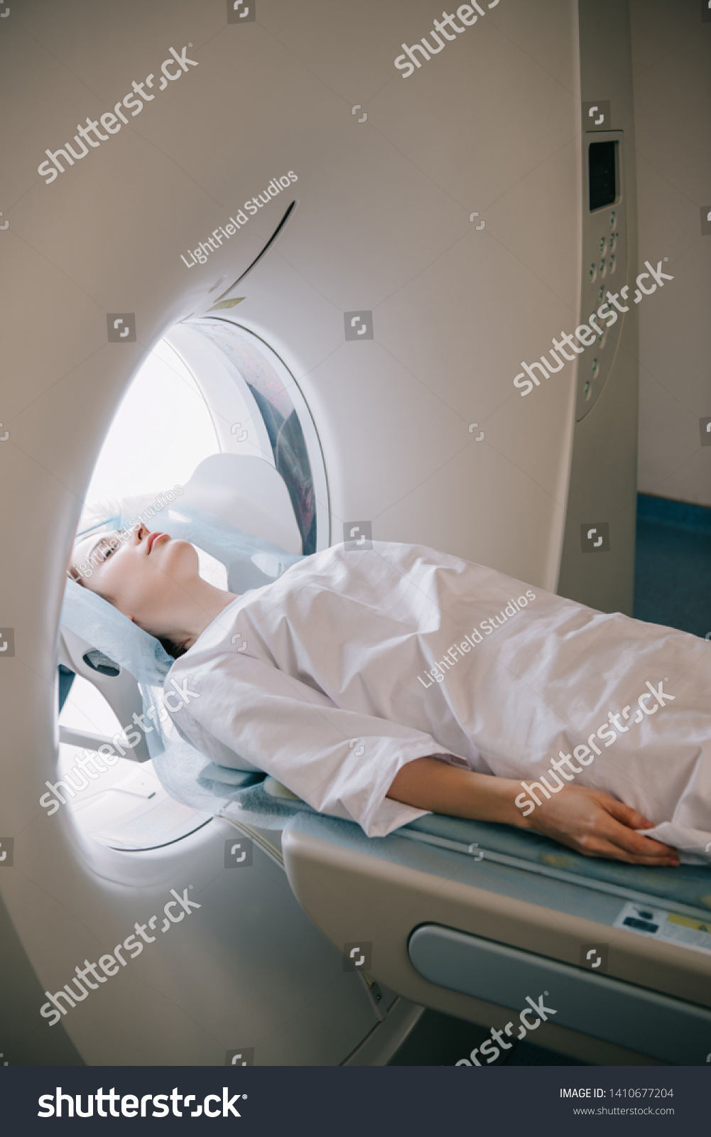woman with closed eyes lying on computed tomography scanner table during radiology test #1410677204