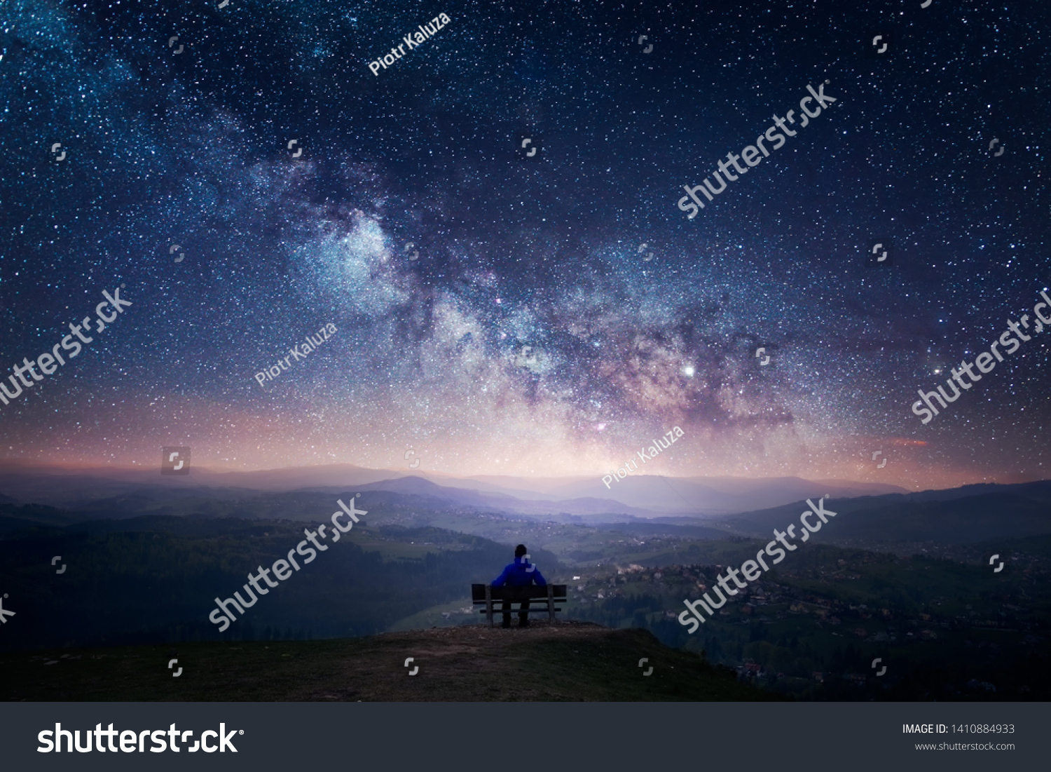 A man sitting on a bench staring at a starry sky with a Milky Way and a mountain landscape #1410884933
