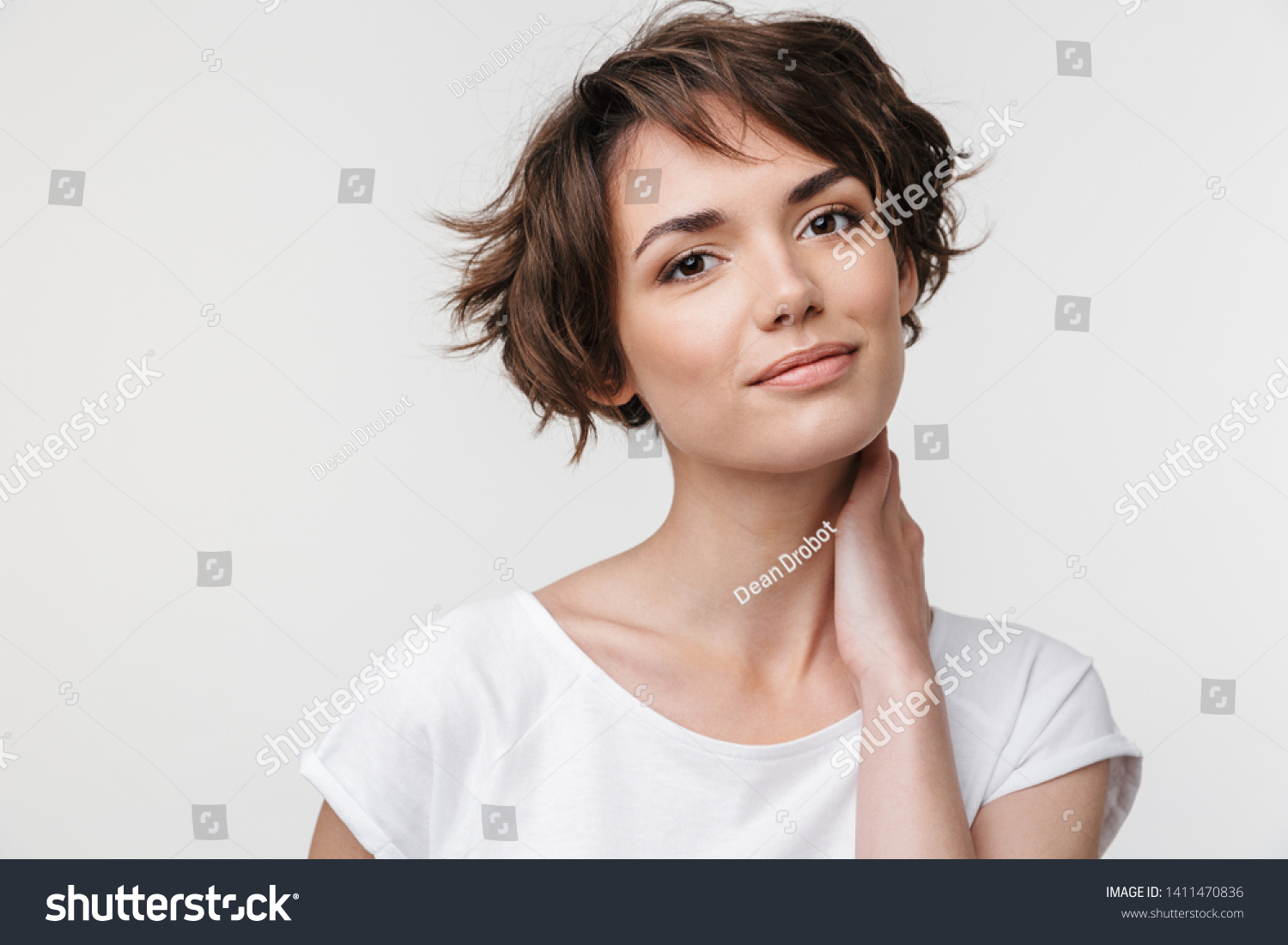 Portrait of pretty woman with short brown hair in basic t-shirt looking at camera while standing isolated over white background #1411470836