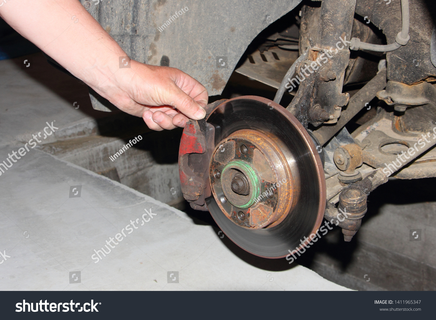 Checking of the brake disc, and brake pads, car brakes inspection - hand points your fingers at the brake caliper #1411965347