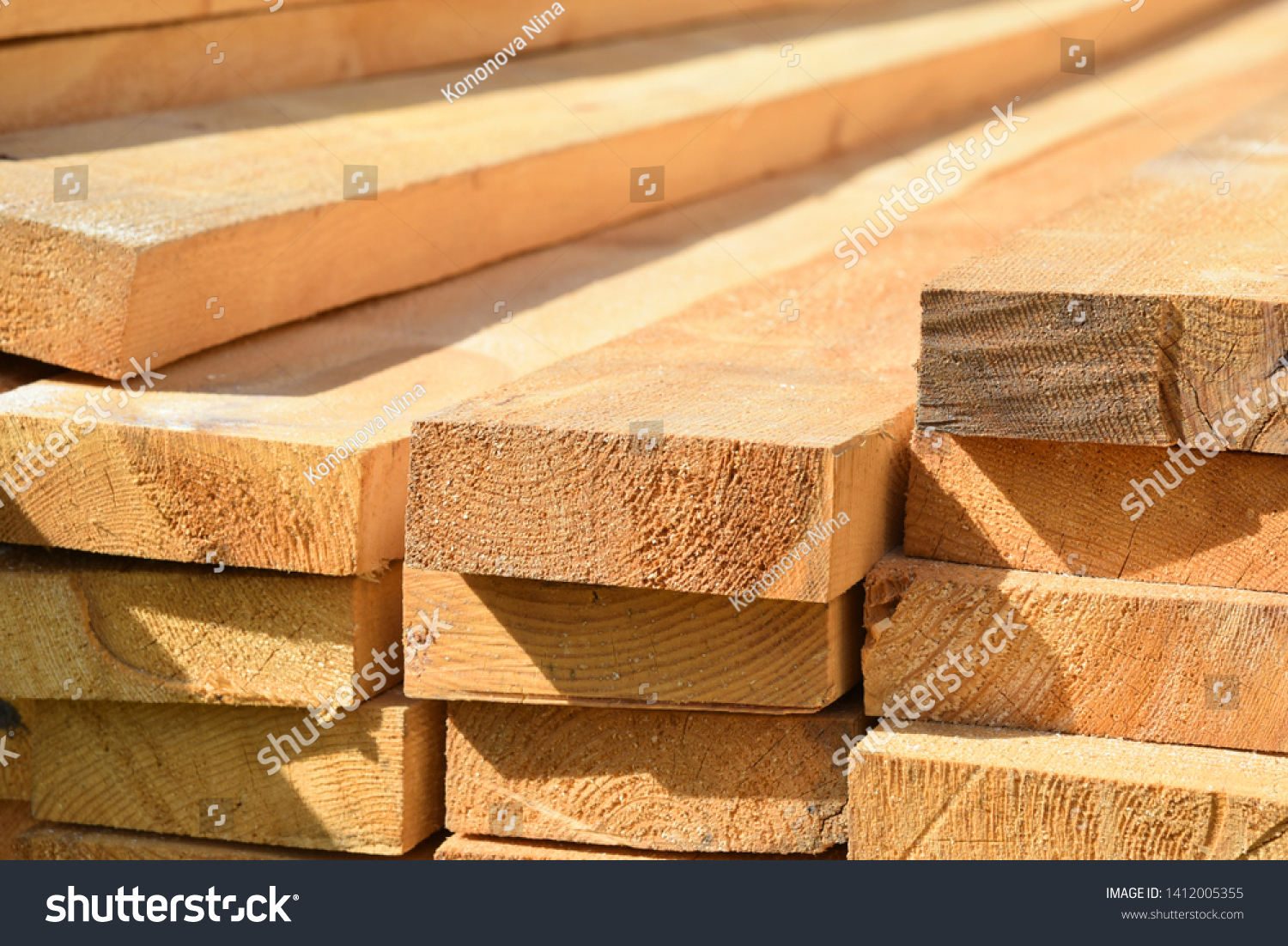 Stacked lumber. Folded wood.Closeup wooden boards.The surface of the end of the board.Lots of planks stacked on top of each other in the warehouse.Lumber for use in construction. #1412005355