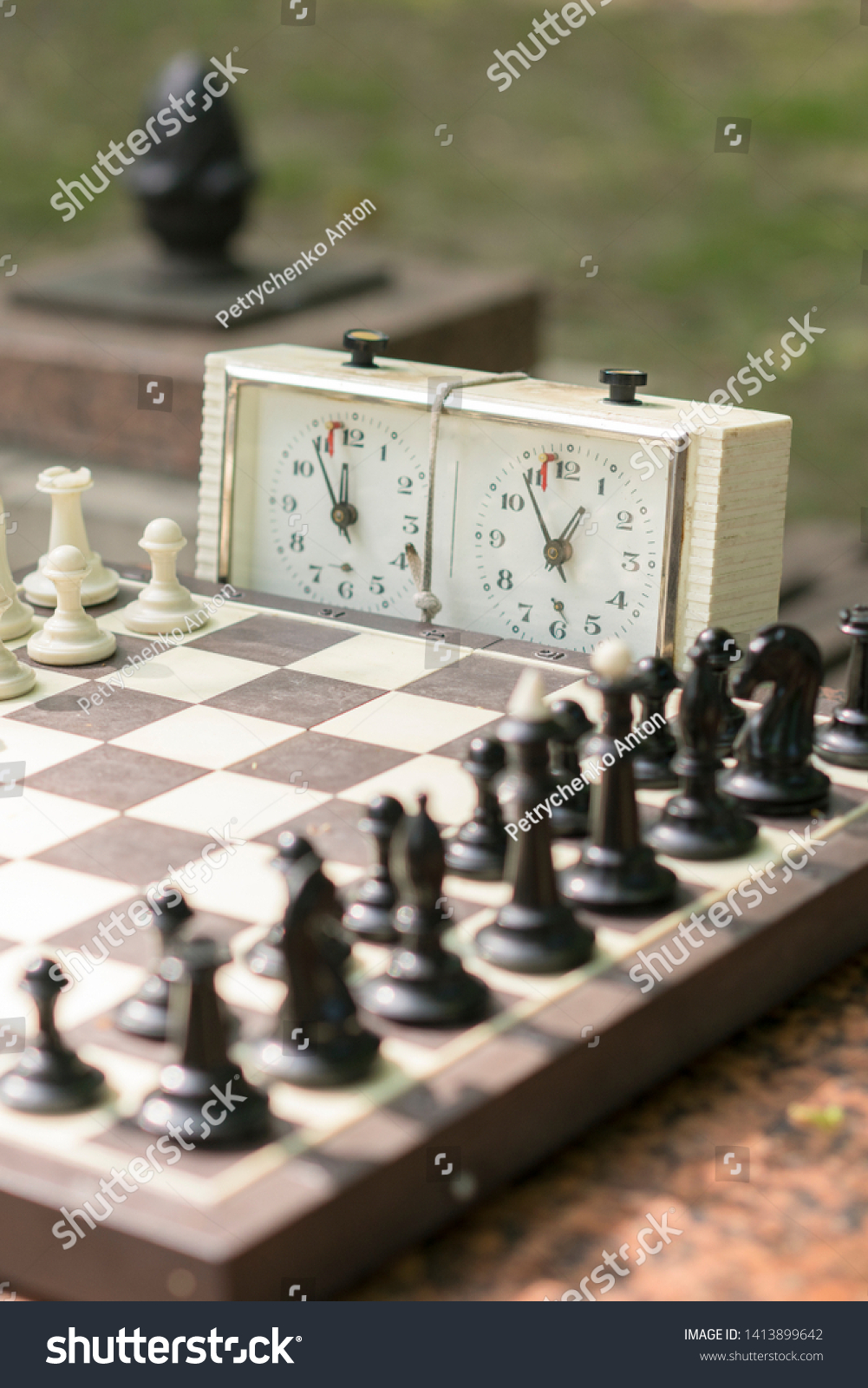 Chess board with pieces and clock on wooden desk In connection with the chess tournament. Chess tournament with chess clock on wooden table. vertical photo #1413899642