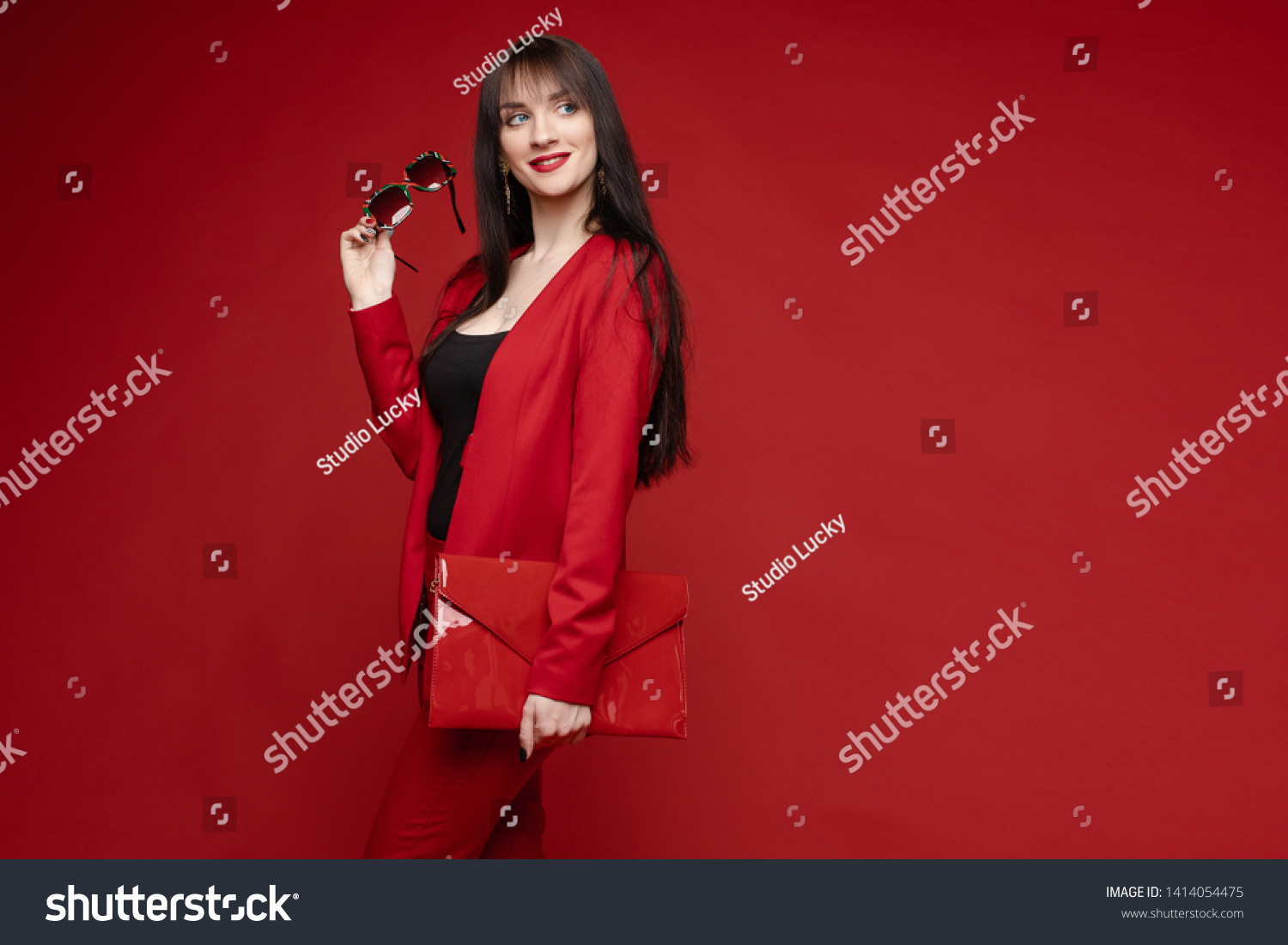 Side view of glamorous brunette posing in red smart suit #1414054475
