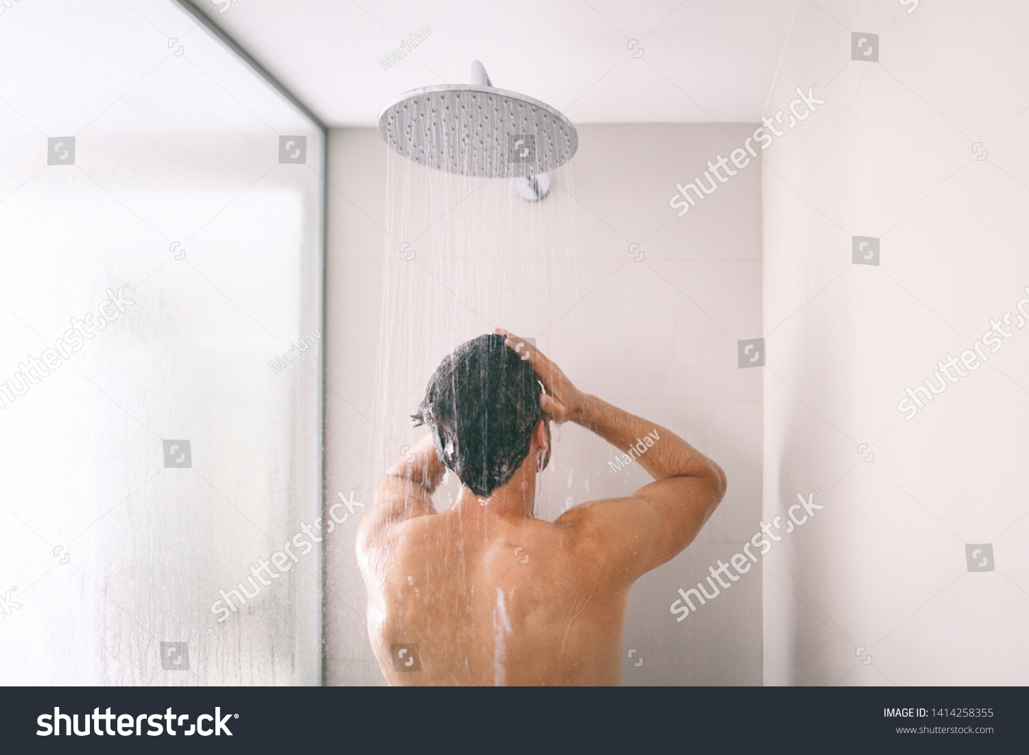 Man taking a shower washing hair with shampoo product under water falling from luxury rain shower head. Morning routine luxury hotel lifestyle guy showering. body care hygiene. #1414258355