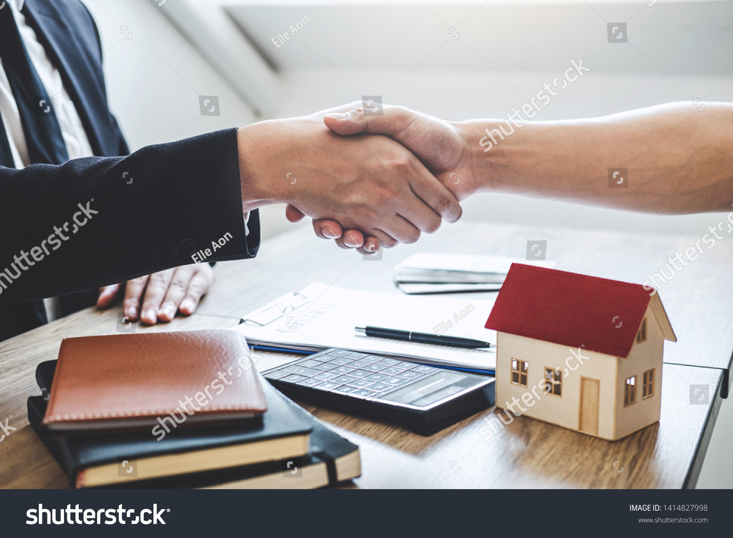 Finishing to successful deal of real estate, Broker and client shaking hands after signing contract approved application form, concerning mortgage loan offer for and house insurance. #1414827998
