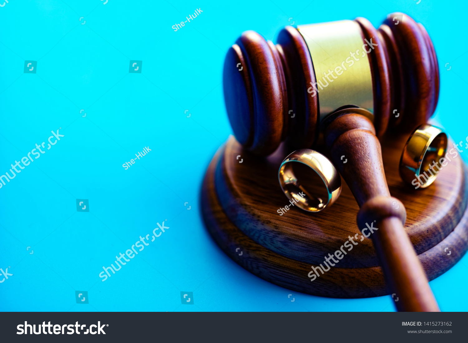 Wedding rings separated by judge hammer. Court decision on divorce concept. #1415273162