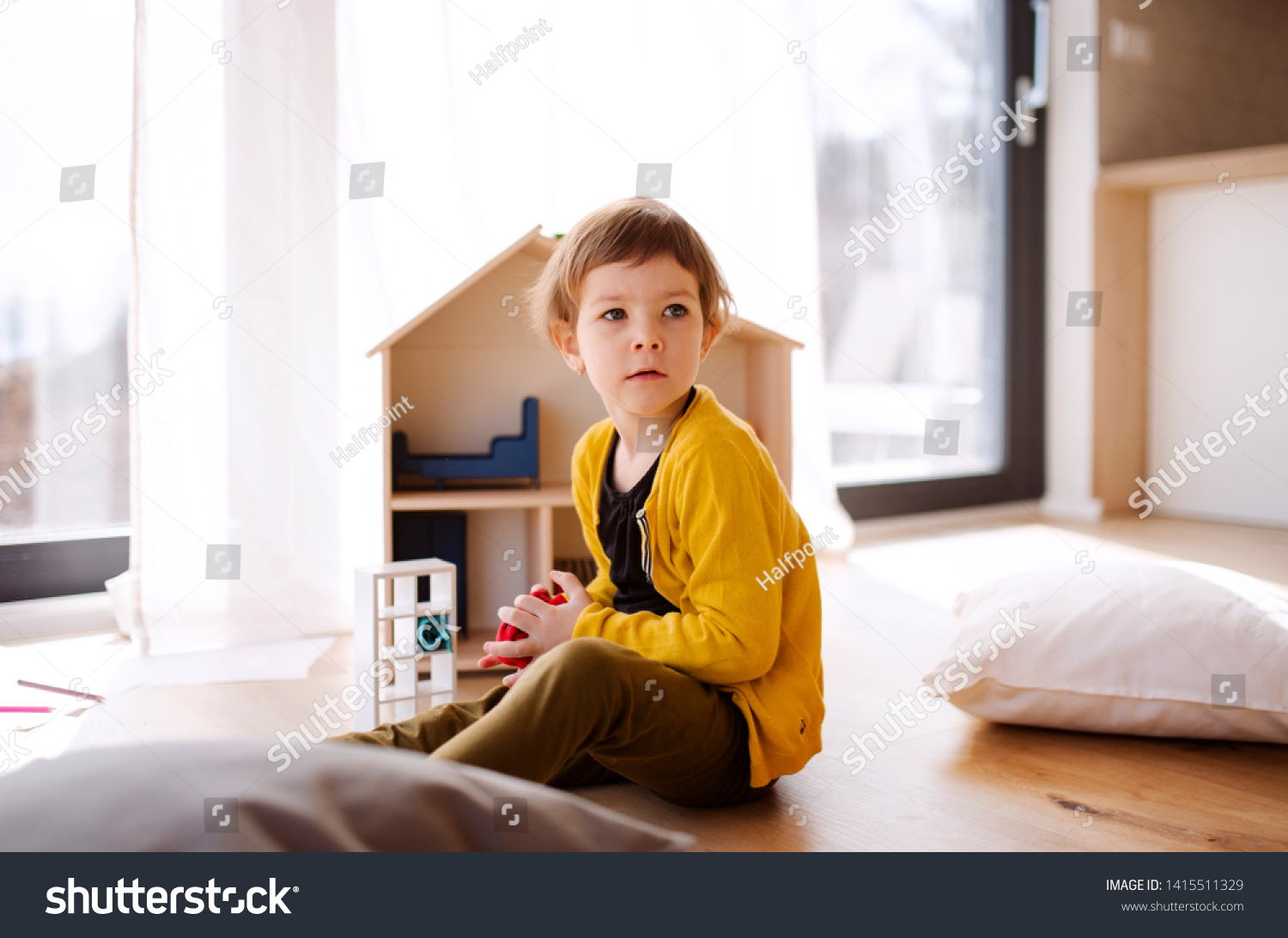 A small girl playing with wooden house on the floor at home. #1415511329