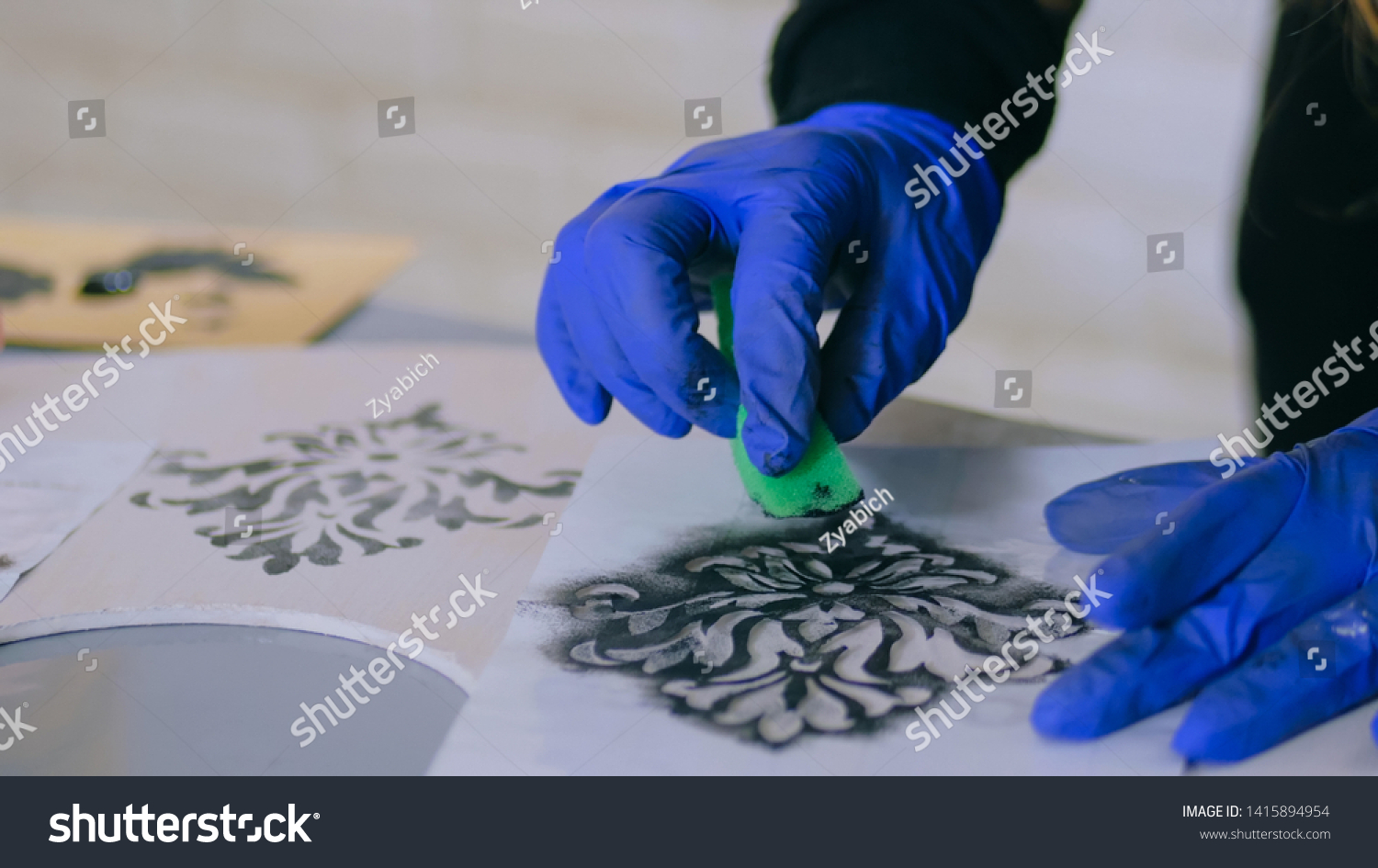 Stencil painting: close up shot of woman hands painting wooden circle. Paint, handmade and crafting work concept #1415894954