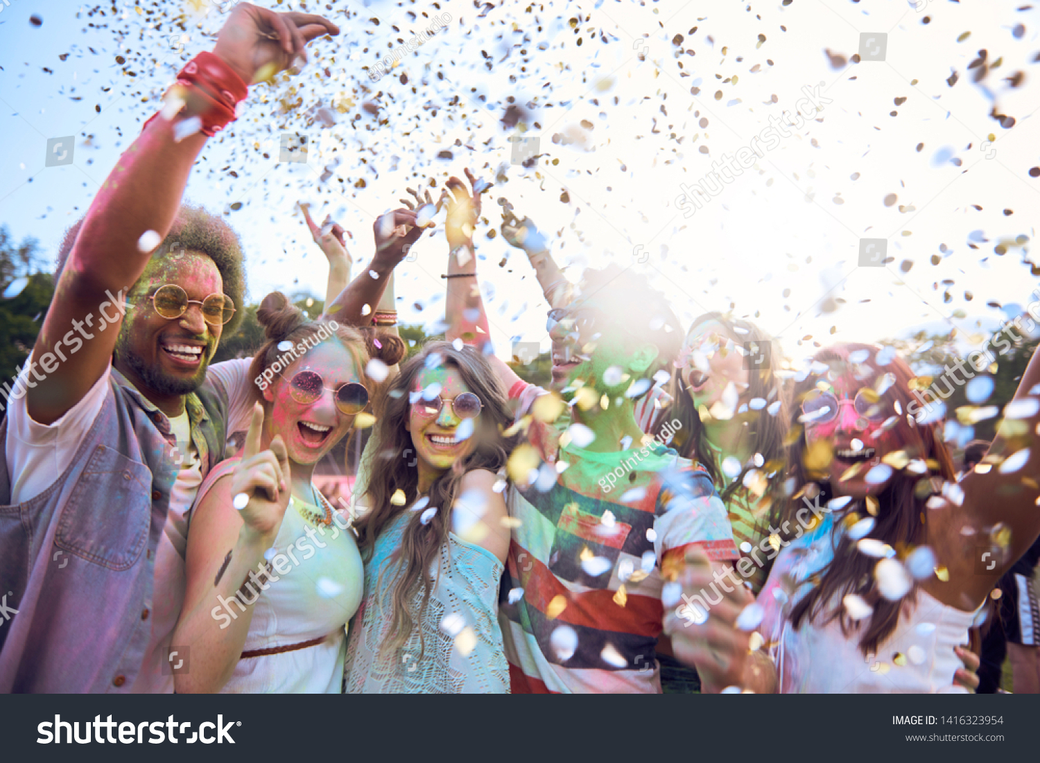 Friends celebrating holi festival under shower of confetti #1416323954