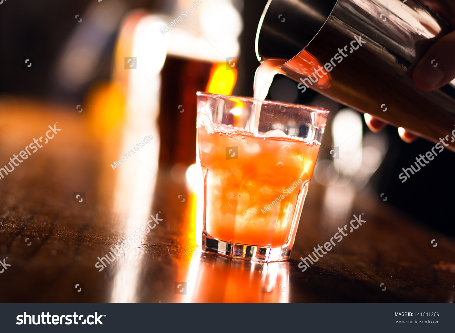 Barman pouring a cocktail into a glass  #141641269
