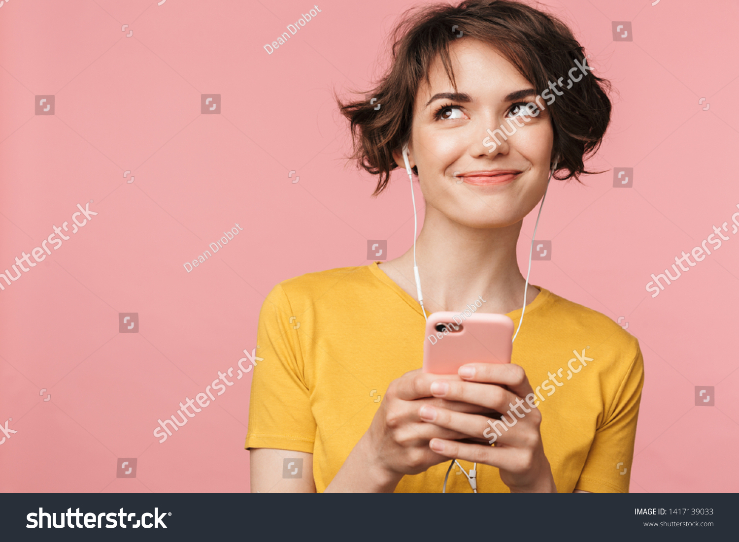 Image of a happy young beautiful woman posing isolated over pink wall background listening music with earphones using mobile phone. #1417139033
