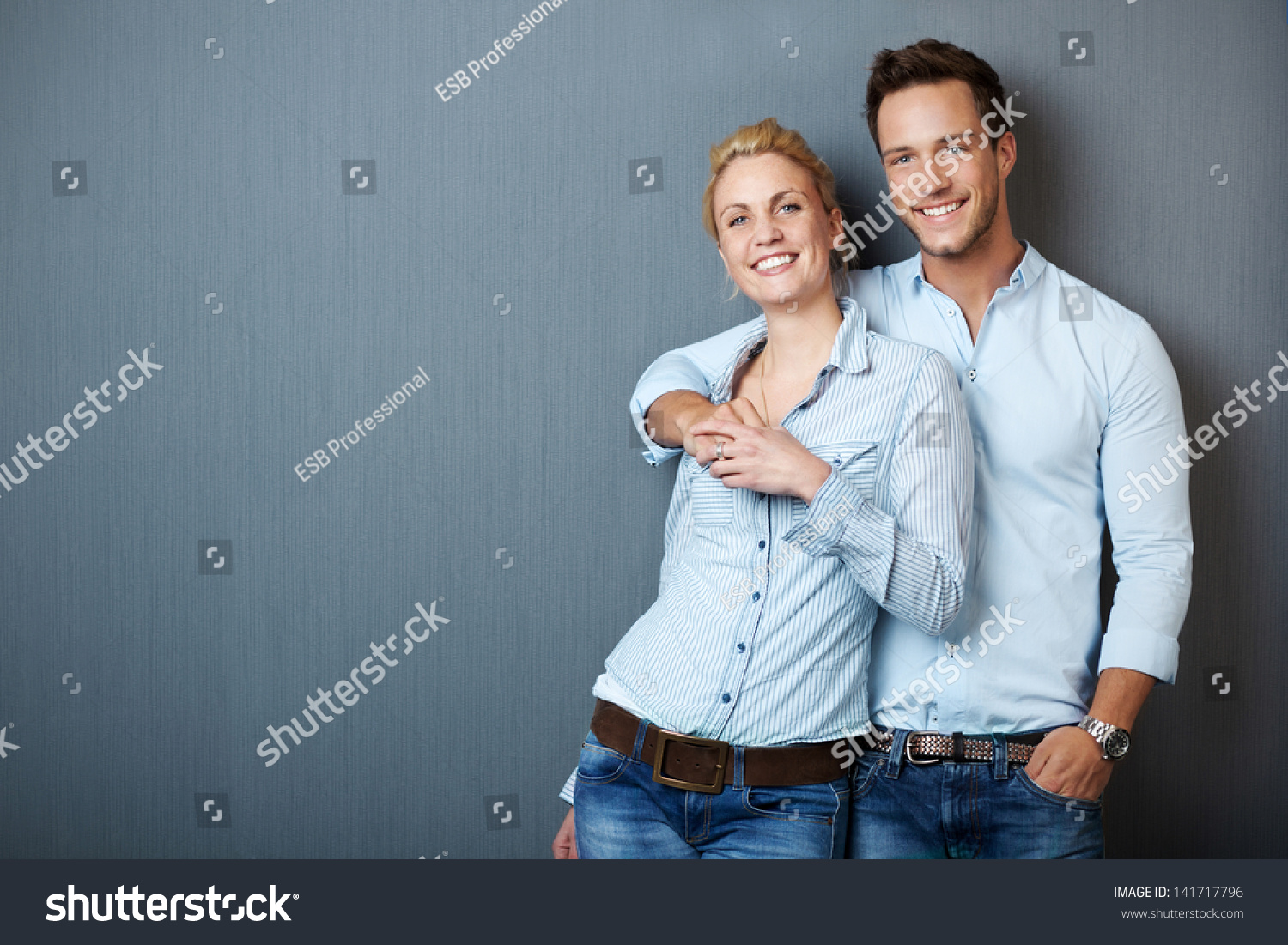Portrait of a young couple standing against blue gray background #141717796