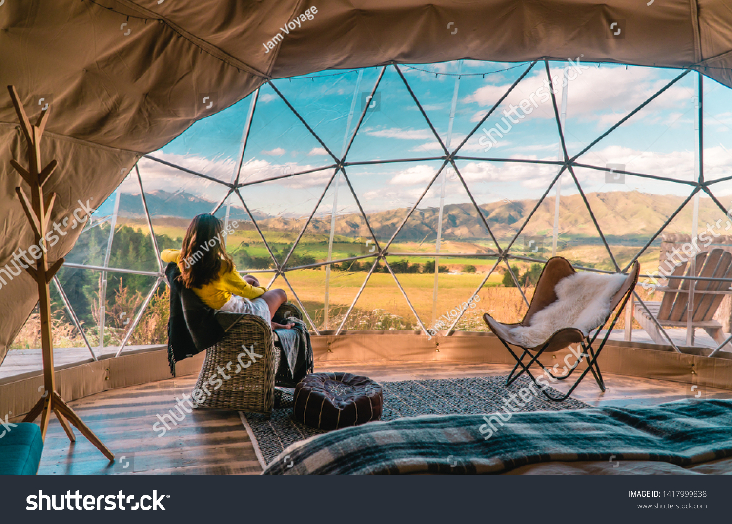 Woman looking out at nature from geo dome tents. Green, blue, orange background. Cozy, camping, glamping, holiday, vacation lifestyle concept. Outdoors cabin, scenic background. New Zealand. #1417999838