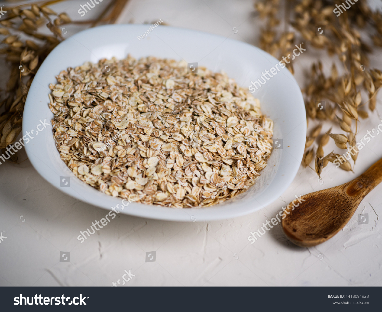 Oat flakes and ears of oats. Oatmeal in a plate on the table. Healthy breakfast #1418094923