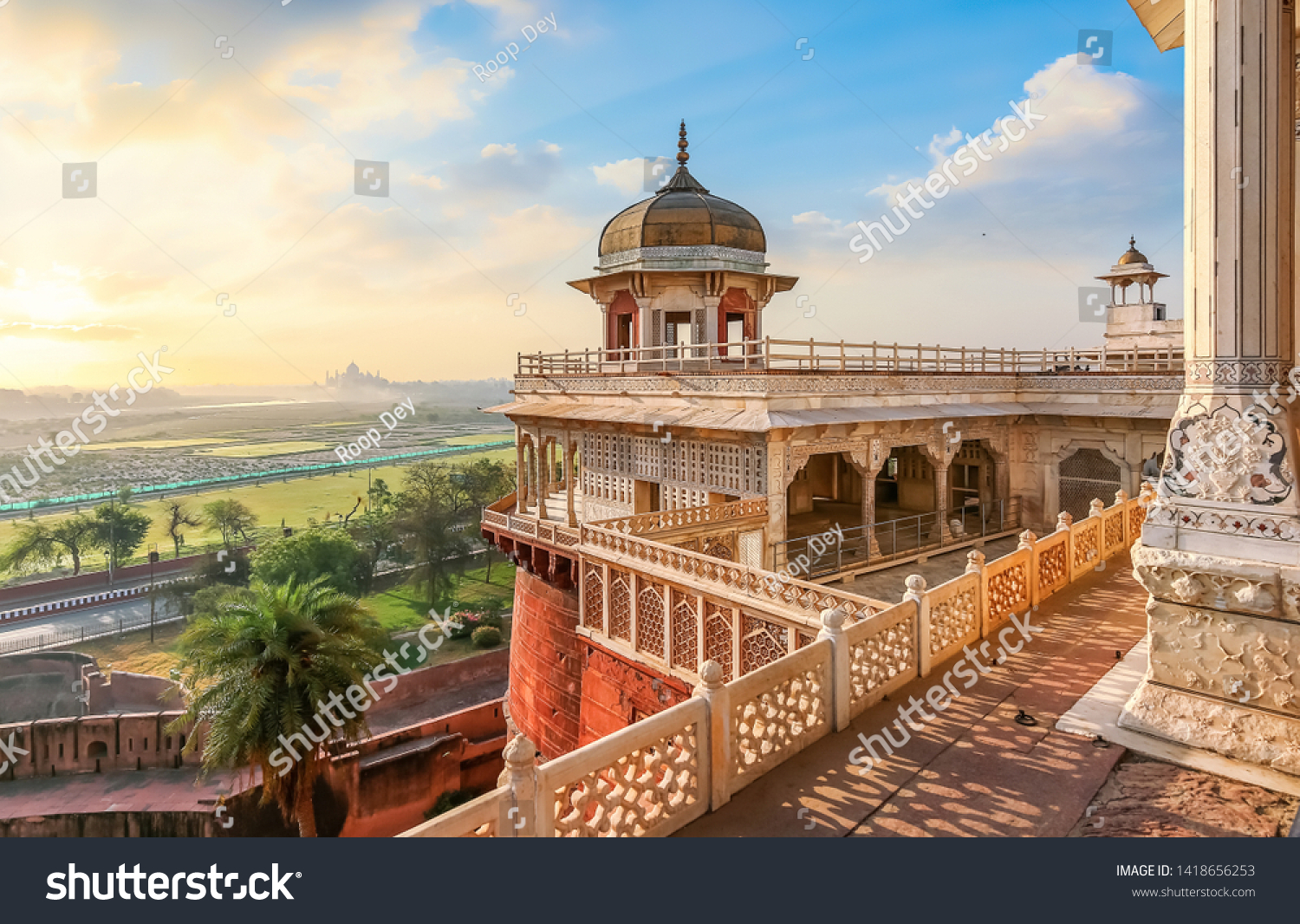 Agra Fort - Medieval Indian fort made of red sandstone and marble with view of dome at sunrise. View of Taj Mahal at a distance as seen from Agra Fort. #1418656253