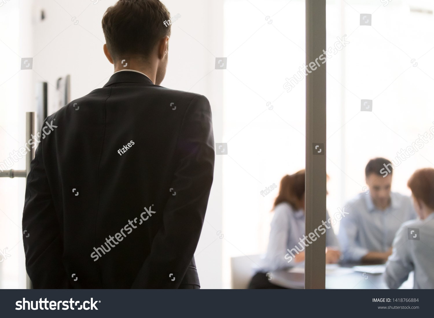 Rear view nervous man standing near glass door waiting looking at participants sitting at desk at business meeting. Lack self-confidence, public speaking fear, stressed applicant before job interview #1418766884