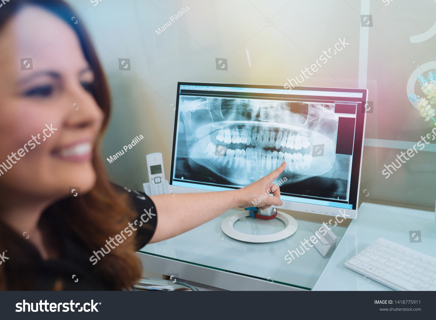 Female dentist showing x-ray footage of teeth to male patient in clinic #1418775911