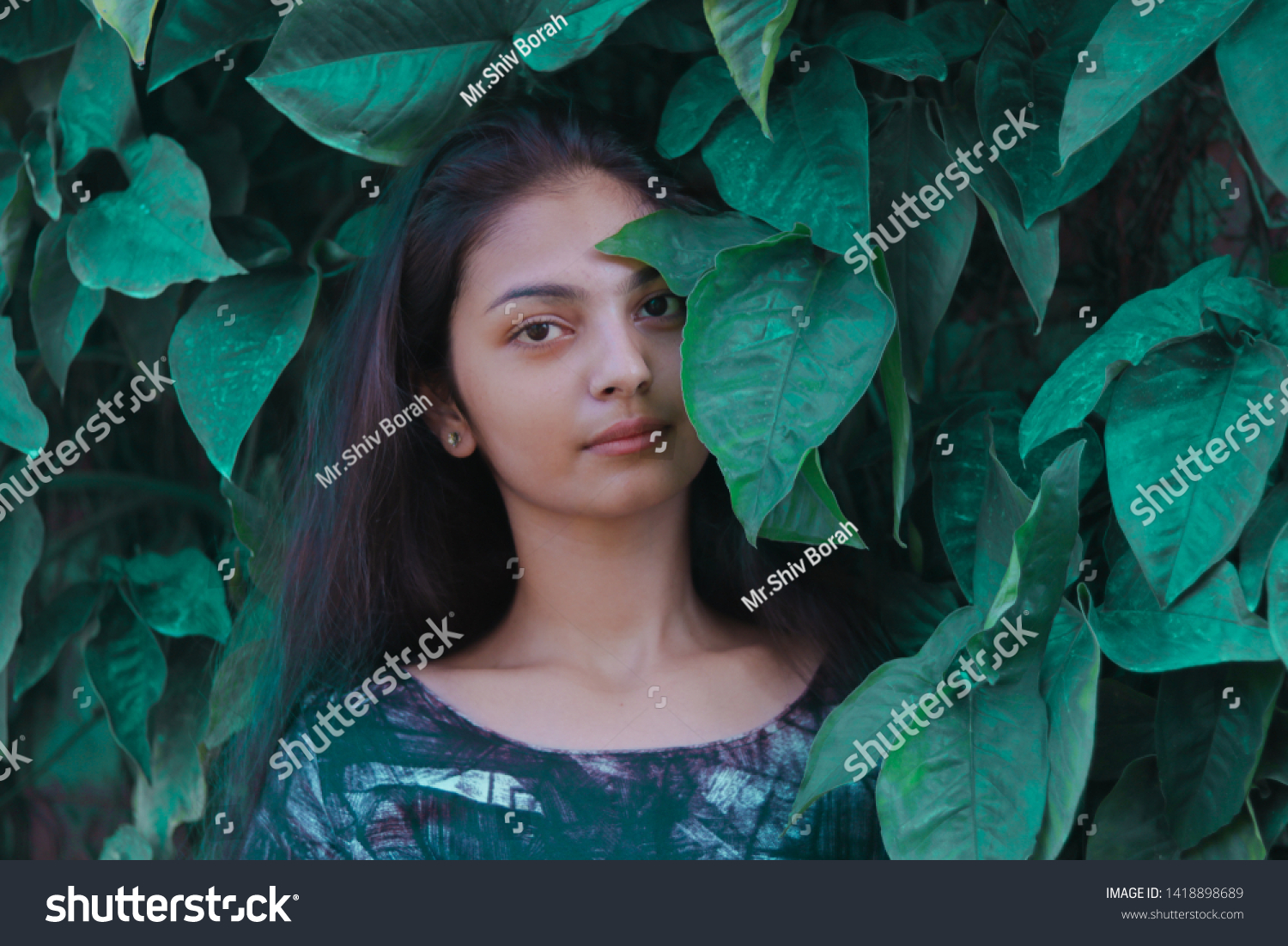 A beautiful girl standing in between leaves. #1418898689