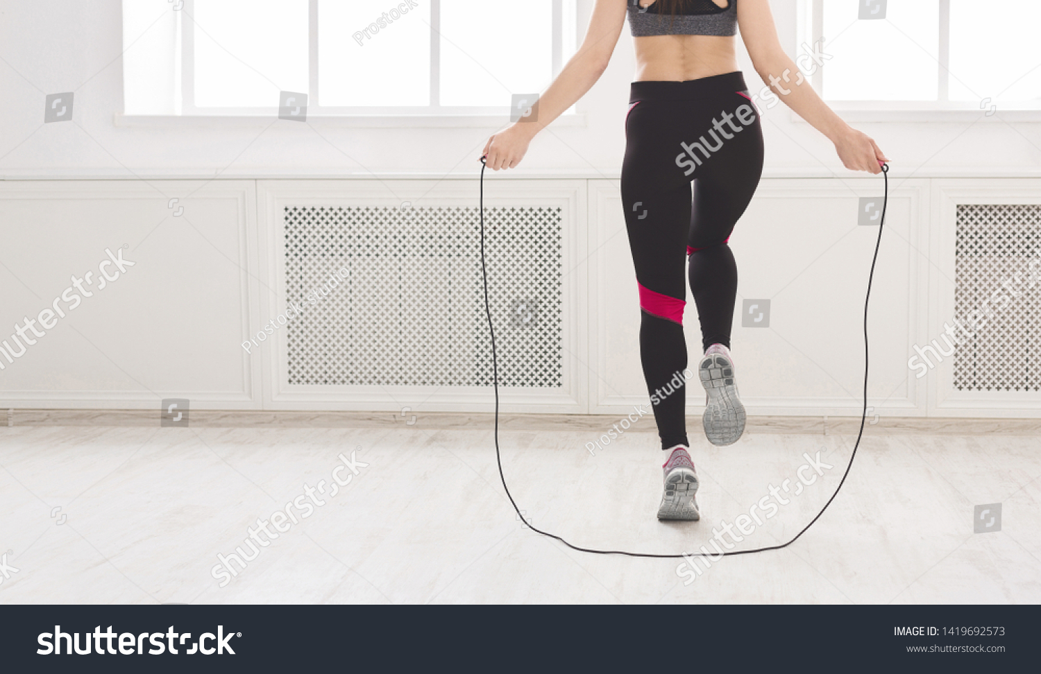 Unrecognizable woman jumping over the skipping rope in studio, crop, panorama, free space #1419692573