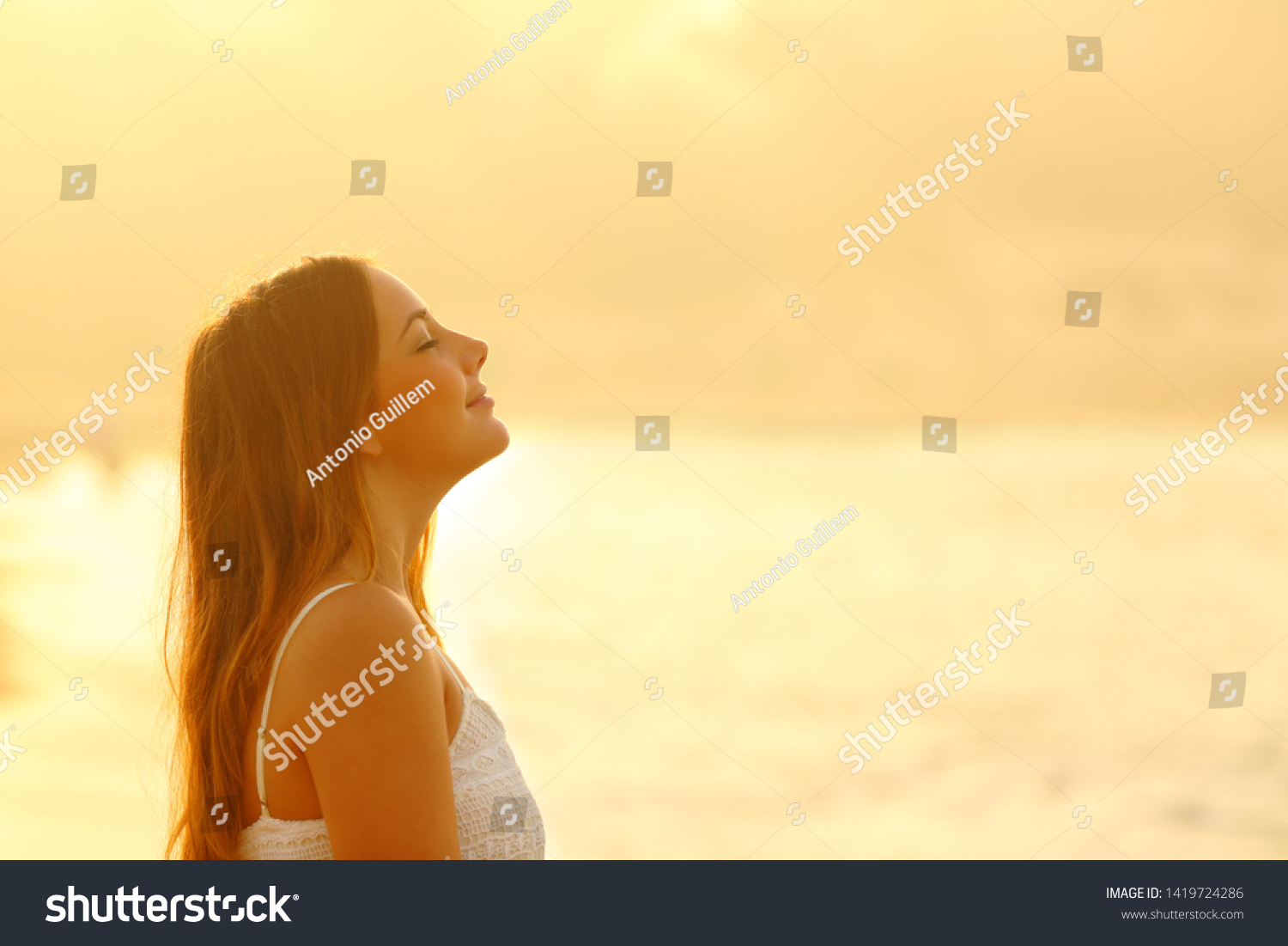 Side view portrait of woman at sunset relaxing breathing fresh air deeply on the beach #1419724286