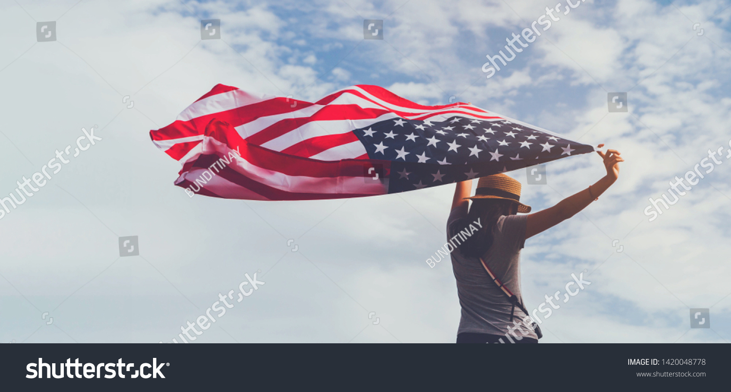 Young woman holding American flag on blue sky background with copy space.Vintage tone.Concept of America celebrate 4th of July. #1420048778