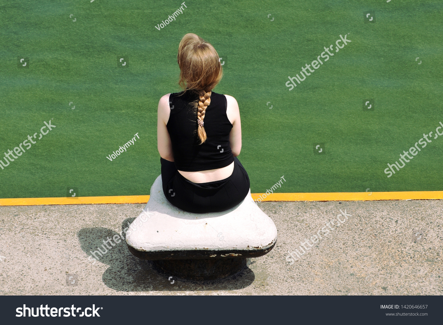 The girl sits on the bollard of sea berth and observes sea flowering which is coloured green #1420646657