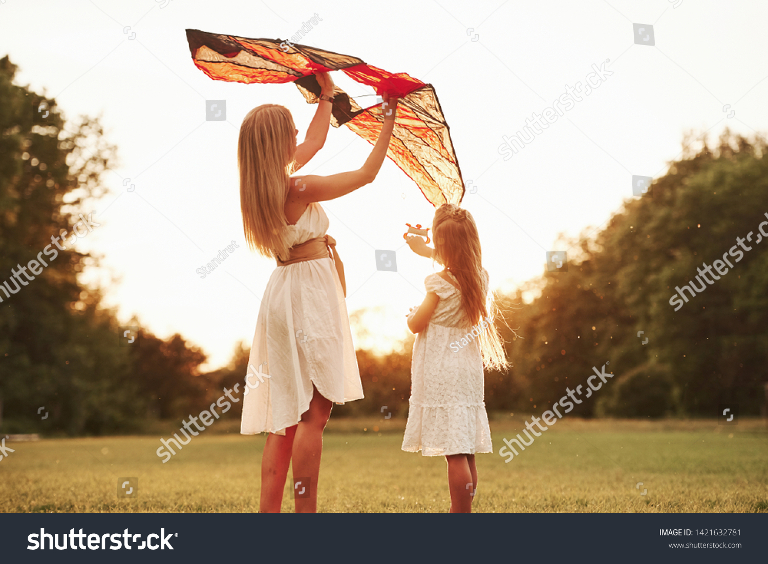 Keep holding it like that. Mother and daughter have fun with kite in the field. Beautiful nature. #1421632781