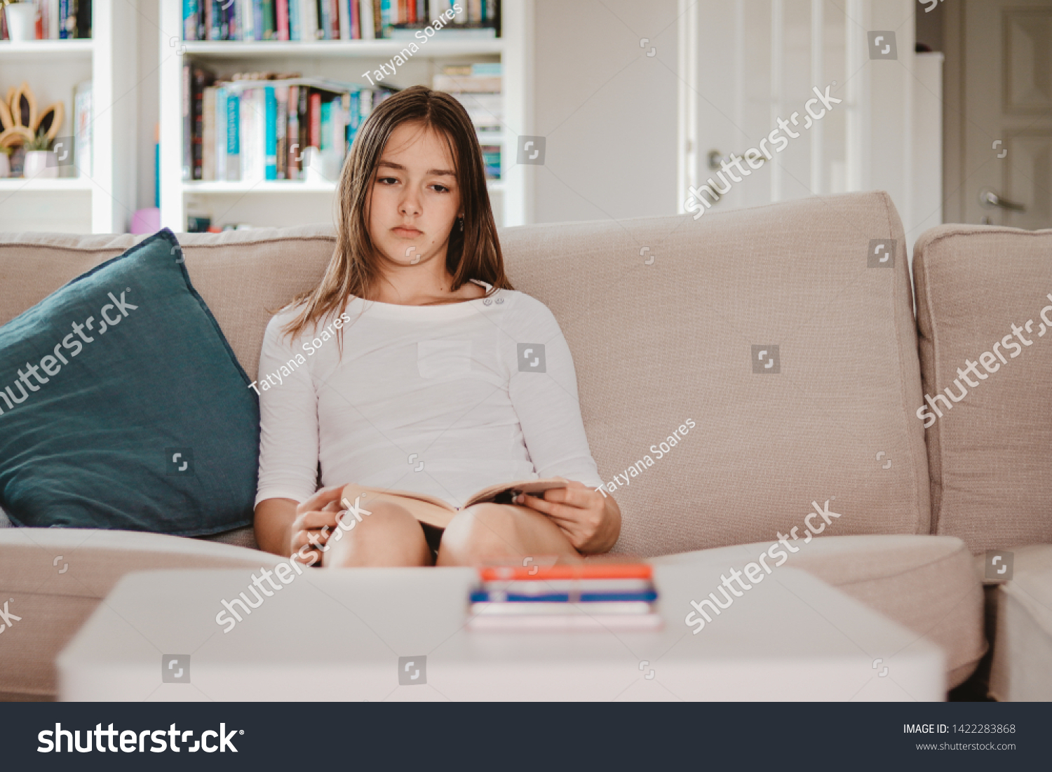 No phone punishment. Upset preteen girl with sad face expression holding book and looking at pile of smartphones at table taken from her. Social media gadget detox. Unplugged. No social network #1422283868