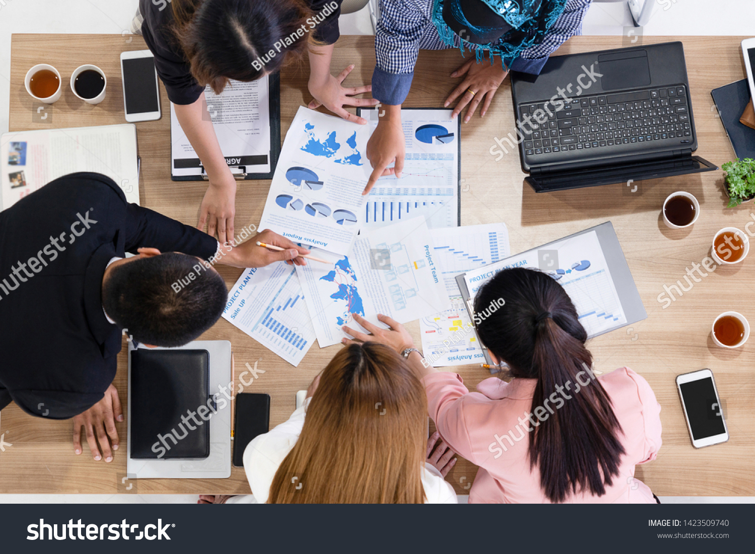 Top view of businessman executive in group meeting with other businessmen and businesswomen in modern office with laptop computer, coffee and document on table. People corporate business team concept. #1423509740