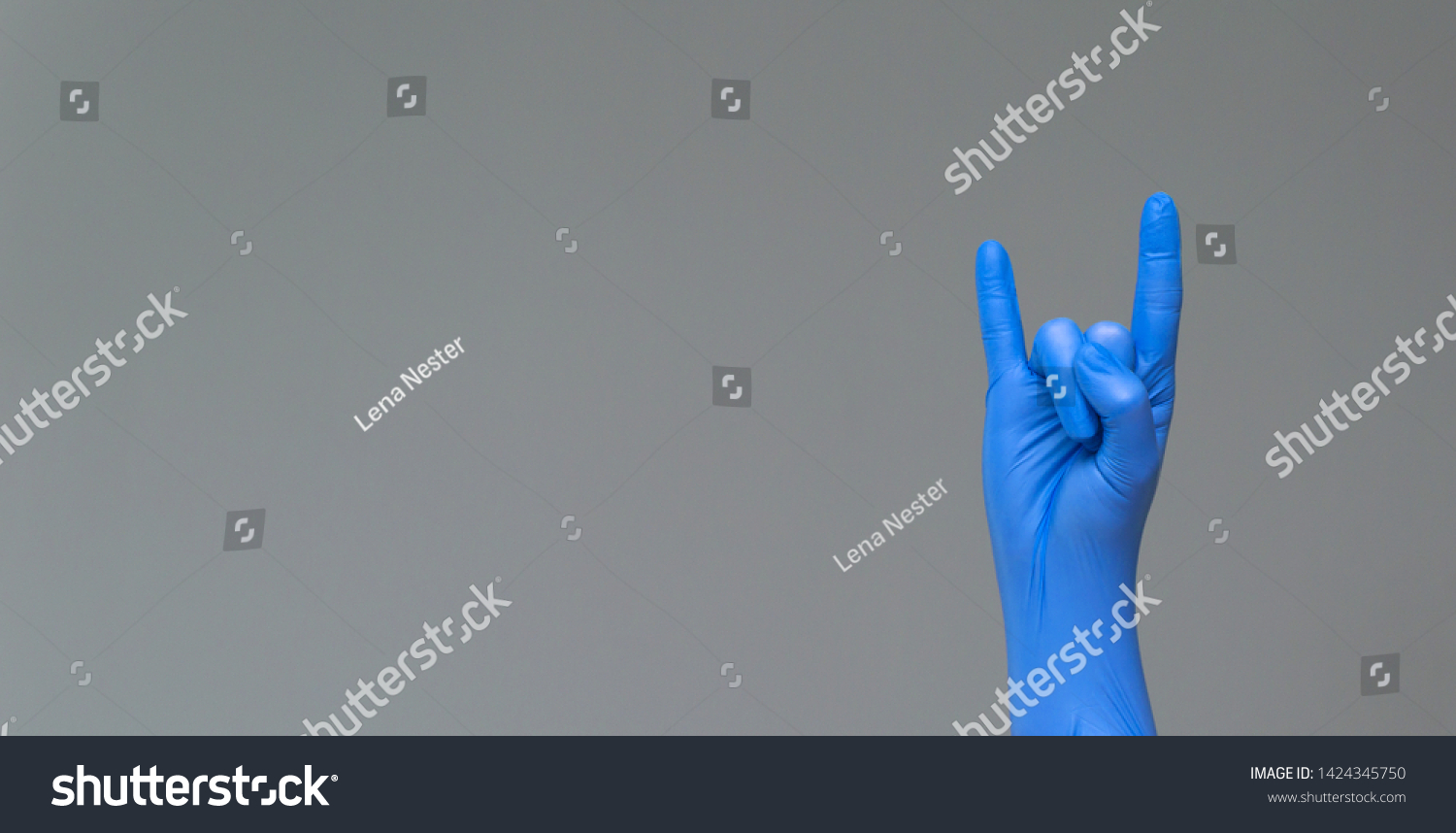 Hand in latex surgical glove, showing the gesture of fans of heavy metal on grey background. Protection concept. COVID-19. #1424345750
