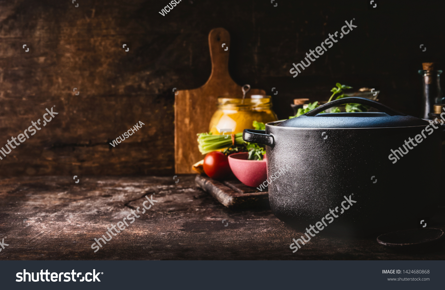 Cast iron pot with fresh herbs, spices and kitchen utensils for tasty cooking on rustic table. Healthy eating. Homemade cooking. Dark. Still life. Food background. Copy space #1424680868