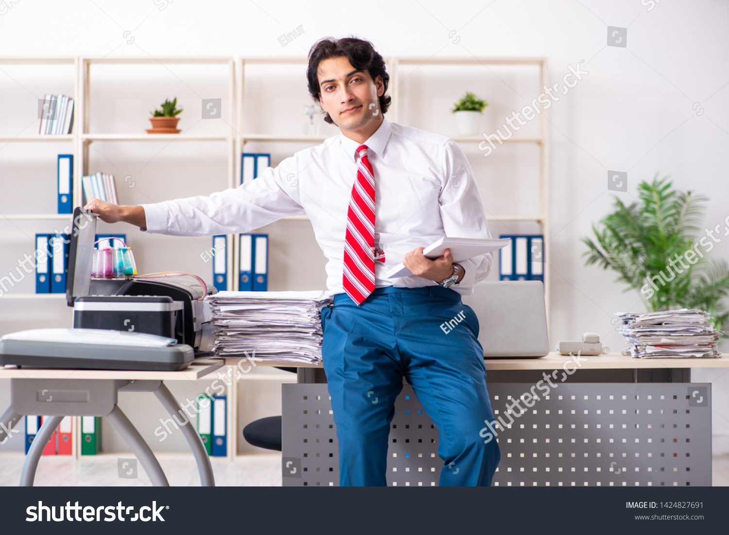 Young employee making copies at copying machine  #1424827691
