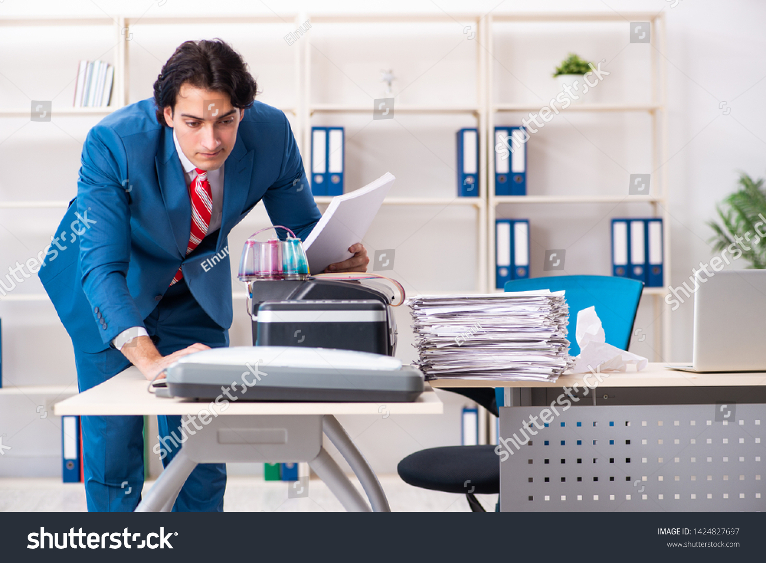 Young employee making copies at copying machine  #1424827697