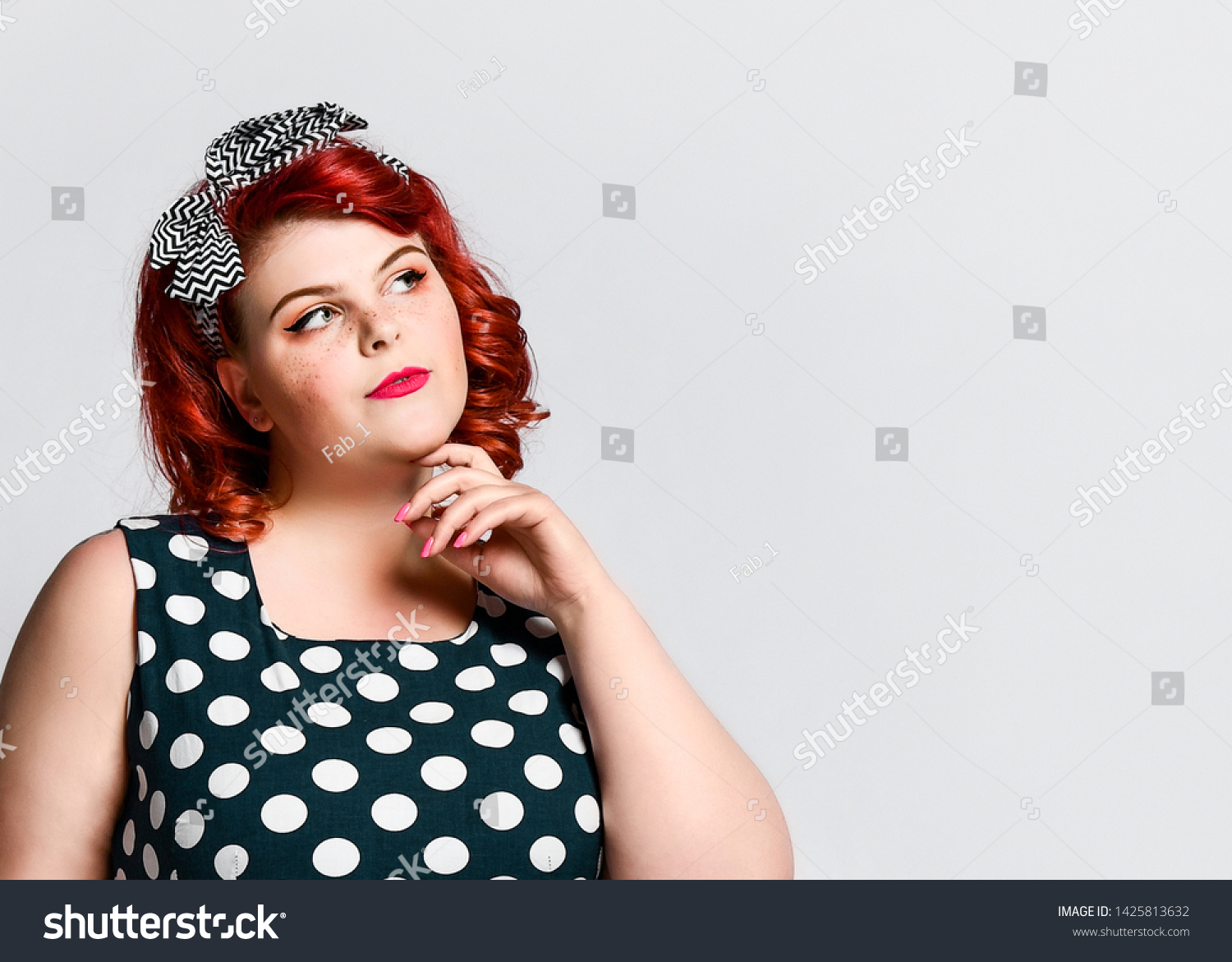 Portrait of a pretty pretty girl in pin-up size plus looking thoughtfully at the side of an empty advertising space #1425813632