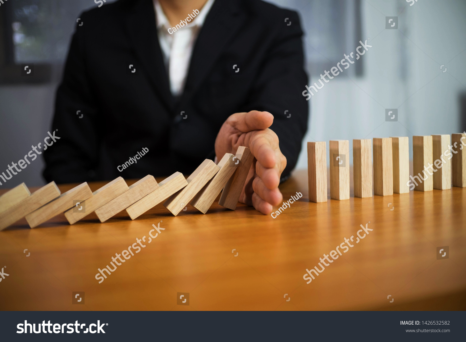 Businessman hand stops domino continuous overturned meaning that hindered business failure. Stop over this business failure concept. #1426532582